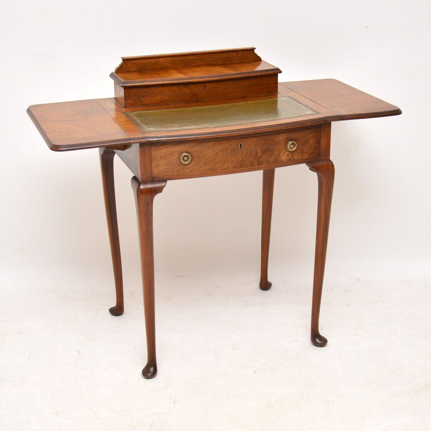 Small antique Edwardian walnut writing table with some very useful features. It’s in excellent original condition and dates from circa 1910 period. This desk has a tooled leather writing surface and useful drop flaps which can extend the top surface