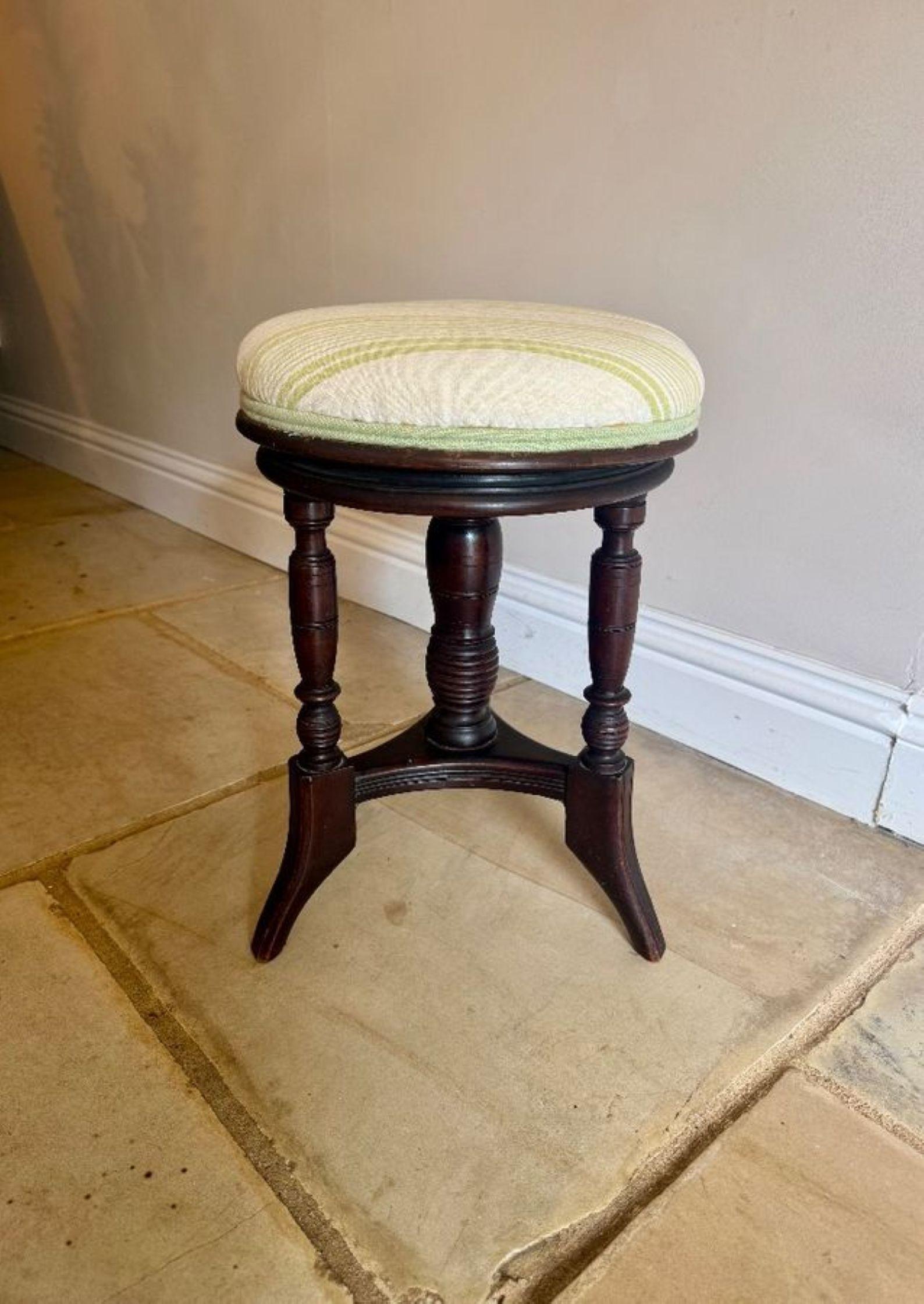 Antique Edwardian mahogany revolving piano stool, having an antique Edwardian revolving piano stool with an upholstered seat in a light green fabric above three turned legs united by curved stretchers. 

D. 1900
