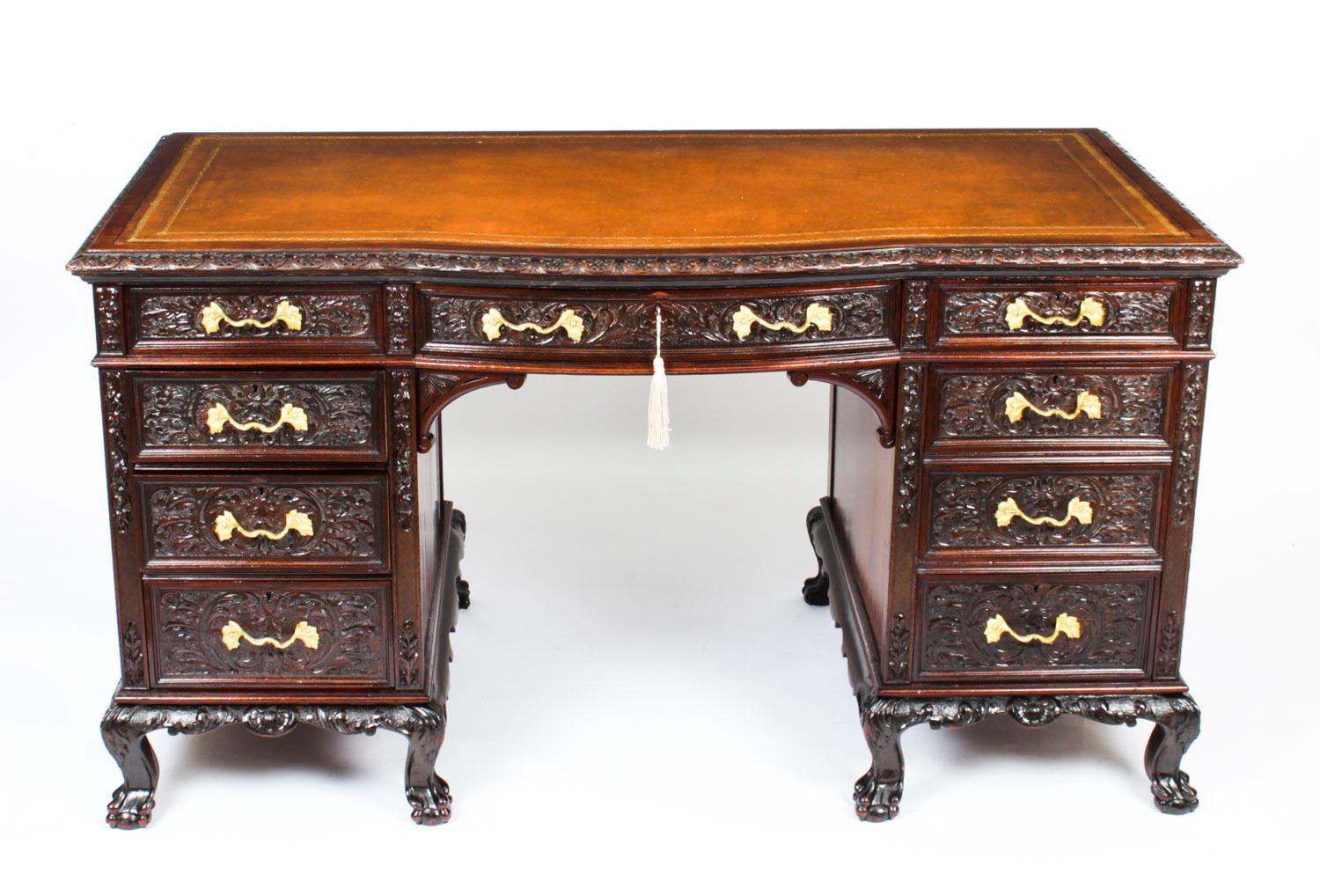 This is a beautiful antique Edwardian Period mahogany kneehole desk, circa 1900 in date.

The desk features a beautifully moulded top with an inset gold tooled tan leather writing surface and foliate carved border, and is serpentine in shape with