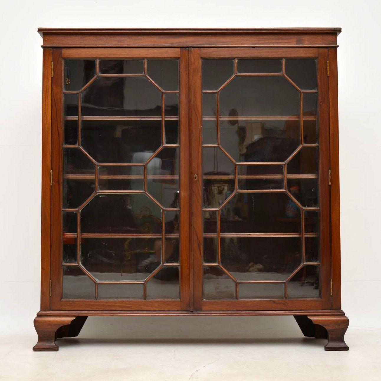 Solid mahogany antique Edwardian two-door bookcase with a reeded top edge, two astral glazed doors and sitting on bold ogee bracket feet. It’s in good original condition and has three adjustable shelves inside. This fine quality bookcase is