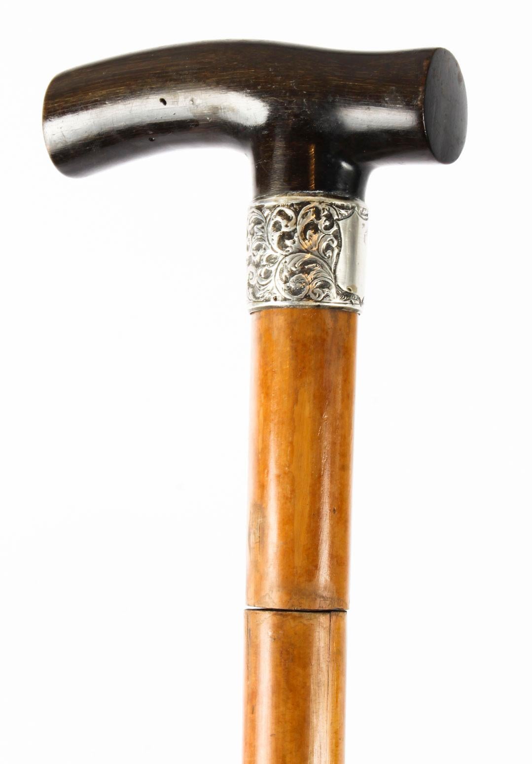 This is a beautiful antique English silver mounted Malacca and horn sword walking stick, bearing hallmarks for Birmingham 1906.

It has an exquisite L-shaped horn handle and features a decorative sterling silver collar with shield.

The Malacca