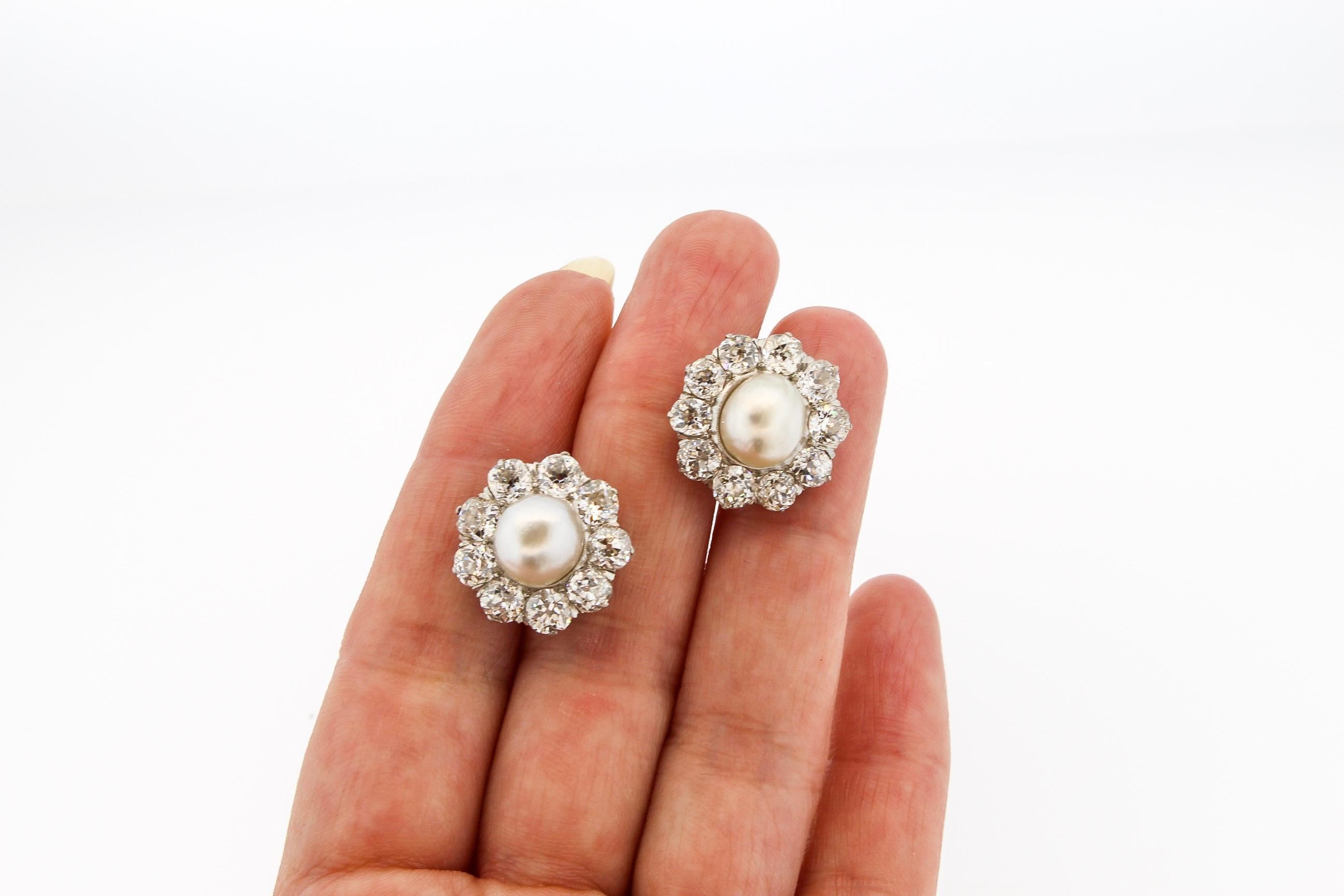 A fabulous pair of platinum and 18k gold natural pearl and old mine diamond cluster earrings. The creamy lustrous natural pearls are surrounded by chunky old mine cut diamonds. The earrings are set with 20 old cut diamonds weighing approximately 6