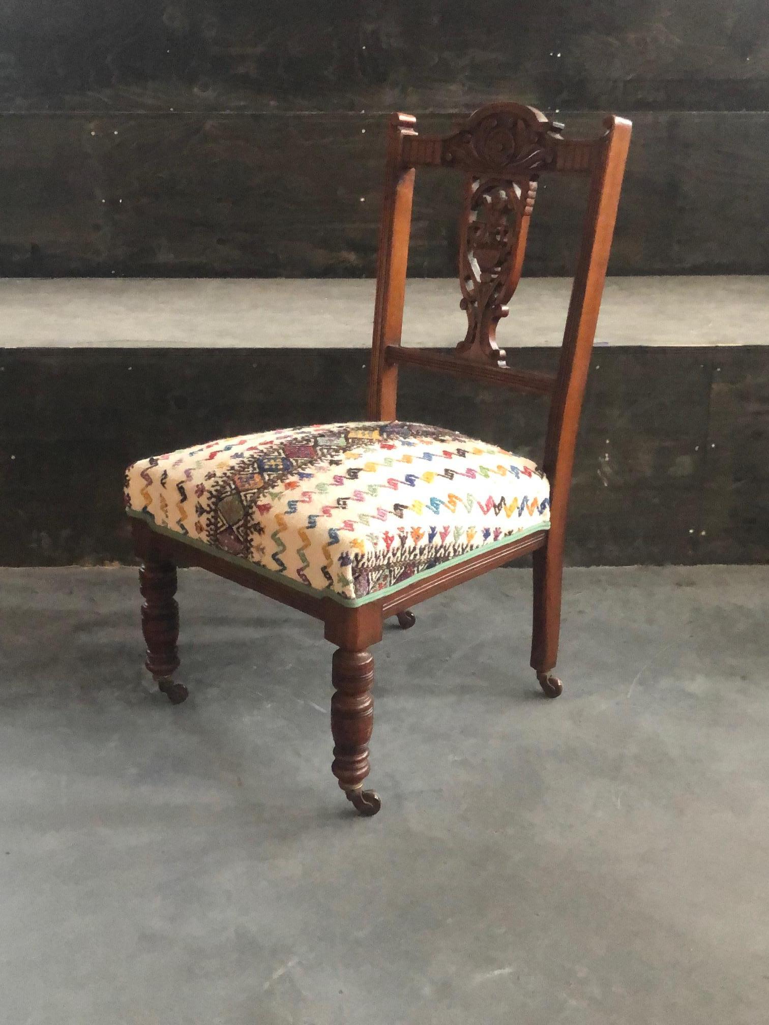 This is an Edwardian nursing chair from the second part of the 19th century (1850-1900) also known as a ‘chauffeuse’ or so-called ‘nursing chair’. It is made from mahogany wood. It has a typical design with short wooden legs on copper wheels. On the