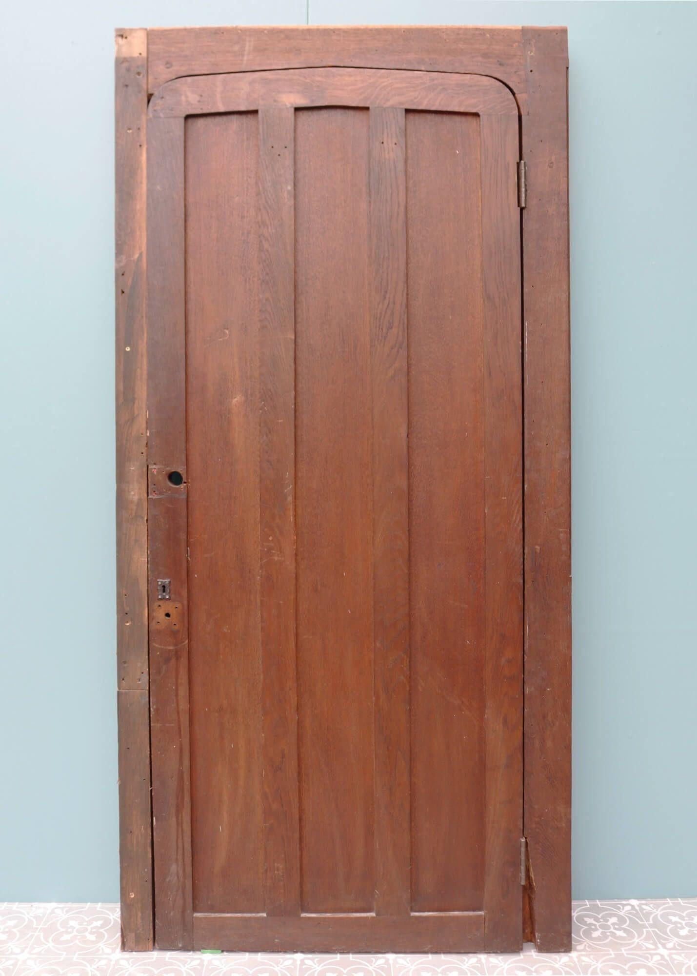 This Edwardian oak door with frame is one of two doors sourced from Rochester Cathedral, the second oldest Cathedral in England. It features a shallow arched door with three shaped, vertical panels within a matching oak frame, once used as an