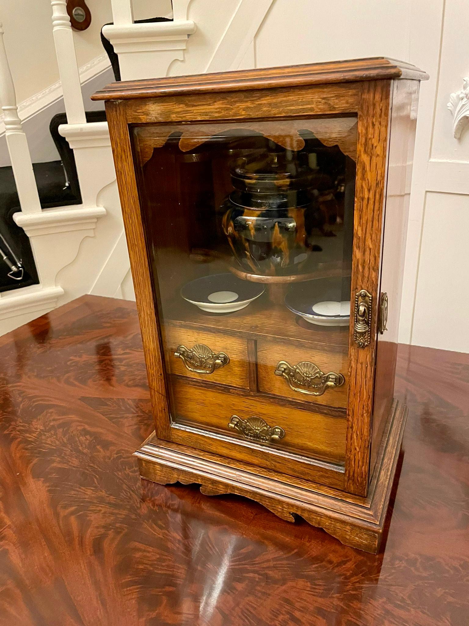 Antique Edwardian oak smokers cabinet having a quality oak top with a moulded edge above a glazed door opening to reveal a fitted interior of three drawers and a china pot, standing on a plinth base.

Measures: 44 x 29 x 21cm 
Date 1900.
    