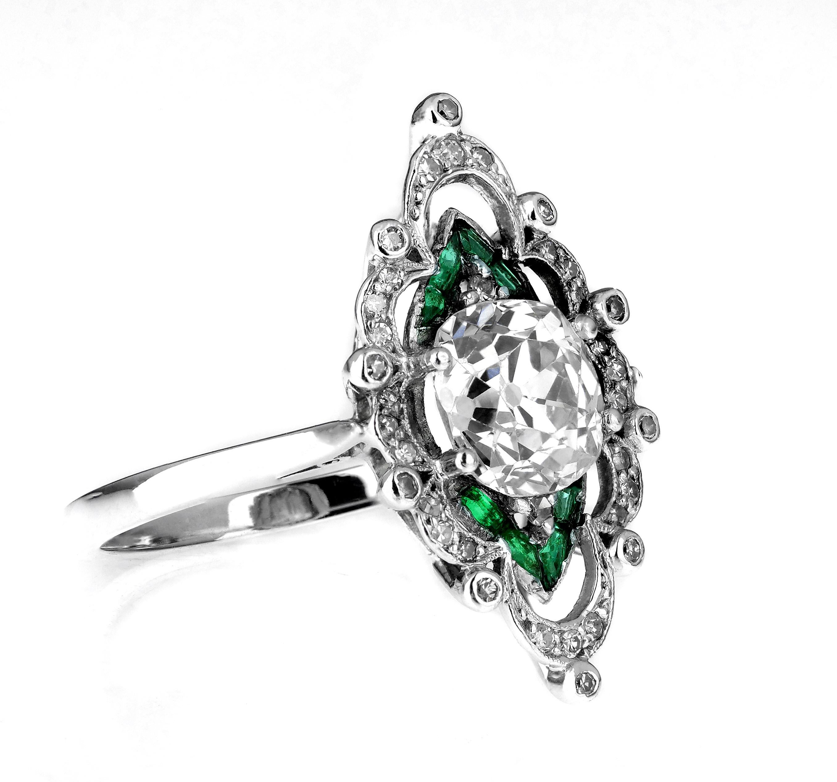 A vibrant Edwardian diamond and emerald ring, set in platinum. Its beautiful design consists of a central set old cushion cut diamond and trillions of emeralds which are surrounded by scrolls of diamonds. 

This ring is a fine example of Edwardian