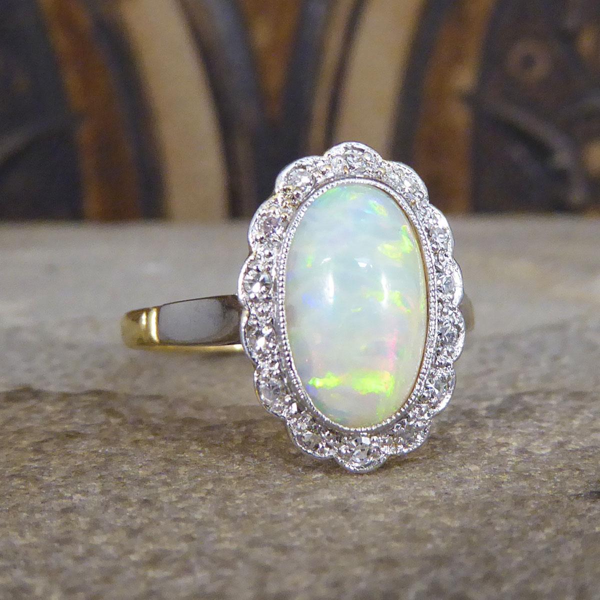 An exquisite and quality ring crafted in the Edwardian era. This wonderful ring features a lustrous Opal in the centre cut in an oval shape with great colours with many greens, blues, oranges and reds, all set in a collar setting with a millegrain