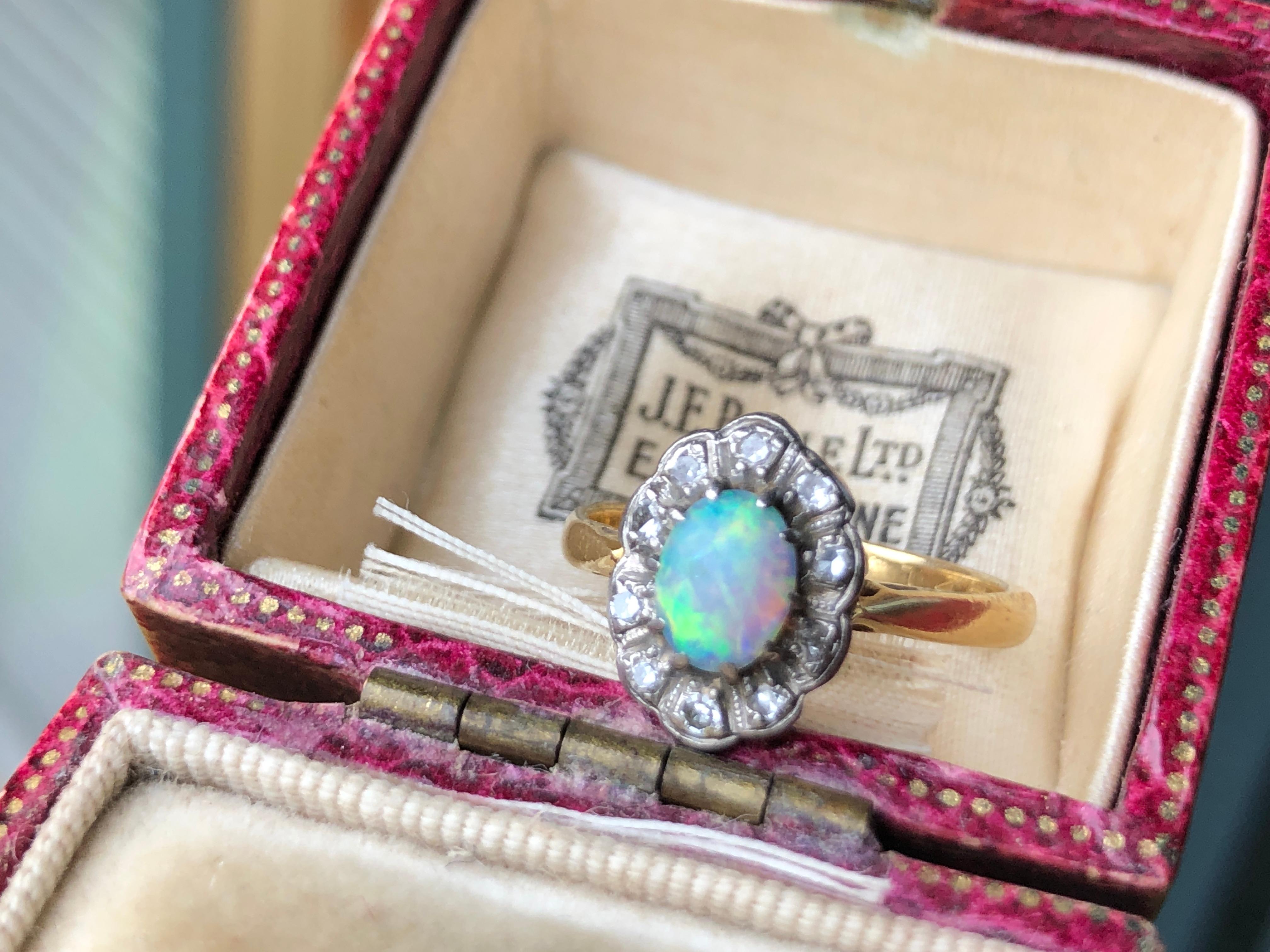 A stunning antique Edwardian ring set with an oval cabochon opal measuring approximately 7 x 4 x 3mm, surrounded by old European-cut diamonds weighing approximately 0.35 carats total. Set in platinum and 18K yellow gold. Circa 1900. 

It is