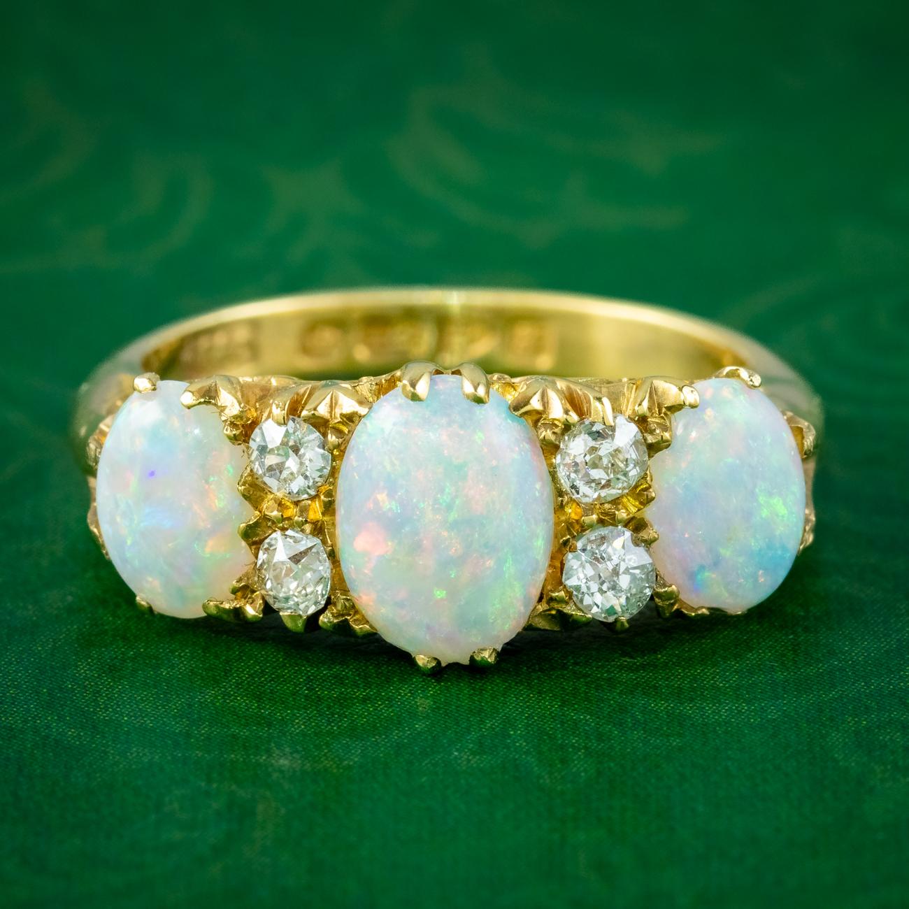 A grand antique Edwardian carved half hoop ring adorned with three natural opal cabochons weighing 1ct in the centre, 0.70ct on either side (approx. 2.4ct total). They display a vibrant rainbow of colours and are complemented by four twinkling old