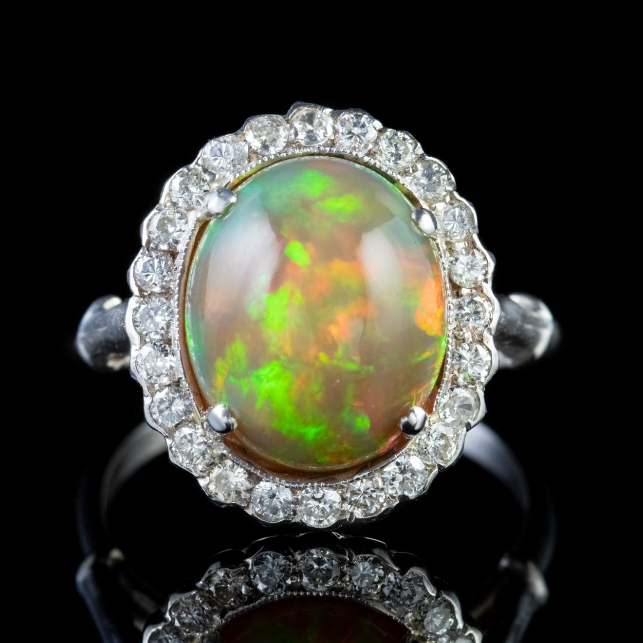 A glorious antique Edwardian cluster ring adorned with a magnificent 6ct natural Opal haloed by a sparkling frame of approx. 1.20ct of old cut Diamonds which complement the central stone beautifully. 

The lovely Opal is a kaleidoscope of rainbow