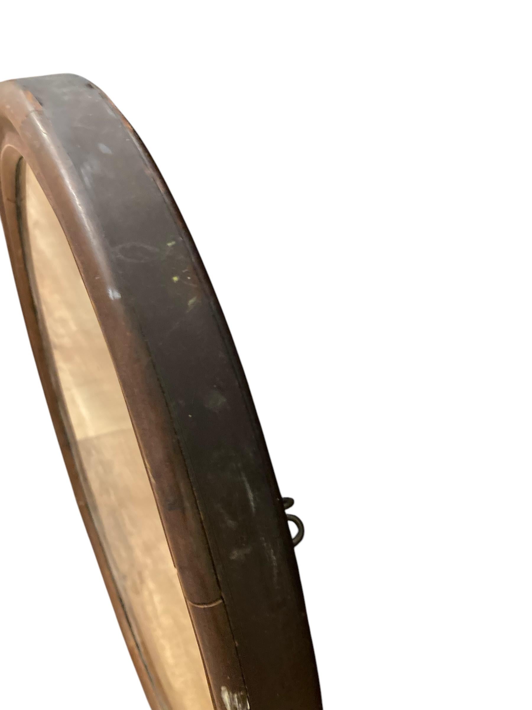 Antique Mirror ovale edoardiano con cornice in mogano. Mostra le staffe laterali originali, come se fosse uno specchio da cassetta. Questo elegante specchio rotondo presenta una cornice in mogano splendidamente lavorata. Ideale per ingressi,