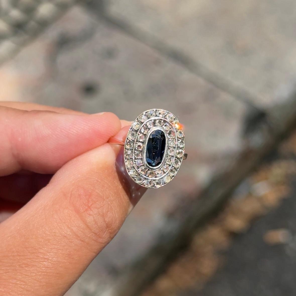 Antique Edwardian sapphire and diamond engagement ring in silver and yellow gold, circa 1900. This remarkable treasure features an elongated oval dark blue sapphire, estimated at 0.90 carats and having probably been mined in Australia over a century