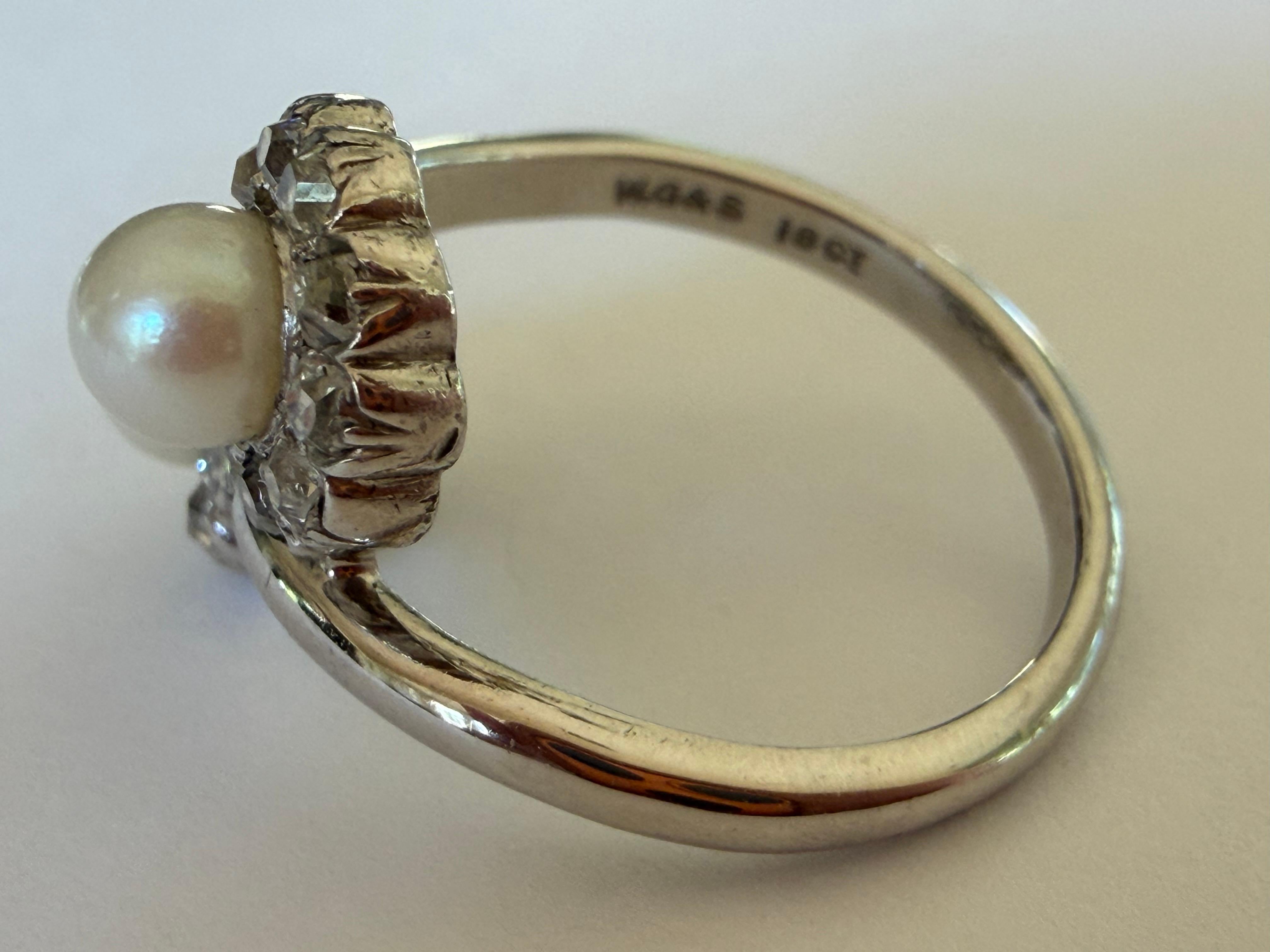 Deux perles blanches naturelles lumineuses mesurant de 4,7 à 4,8 mm se trouvent au centre de cette bague bypass de la période édouardienne, entourée de vingt diamants taillés dans la Nature totalisant environ 1,00 carat, de couleur G-H et de pureté