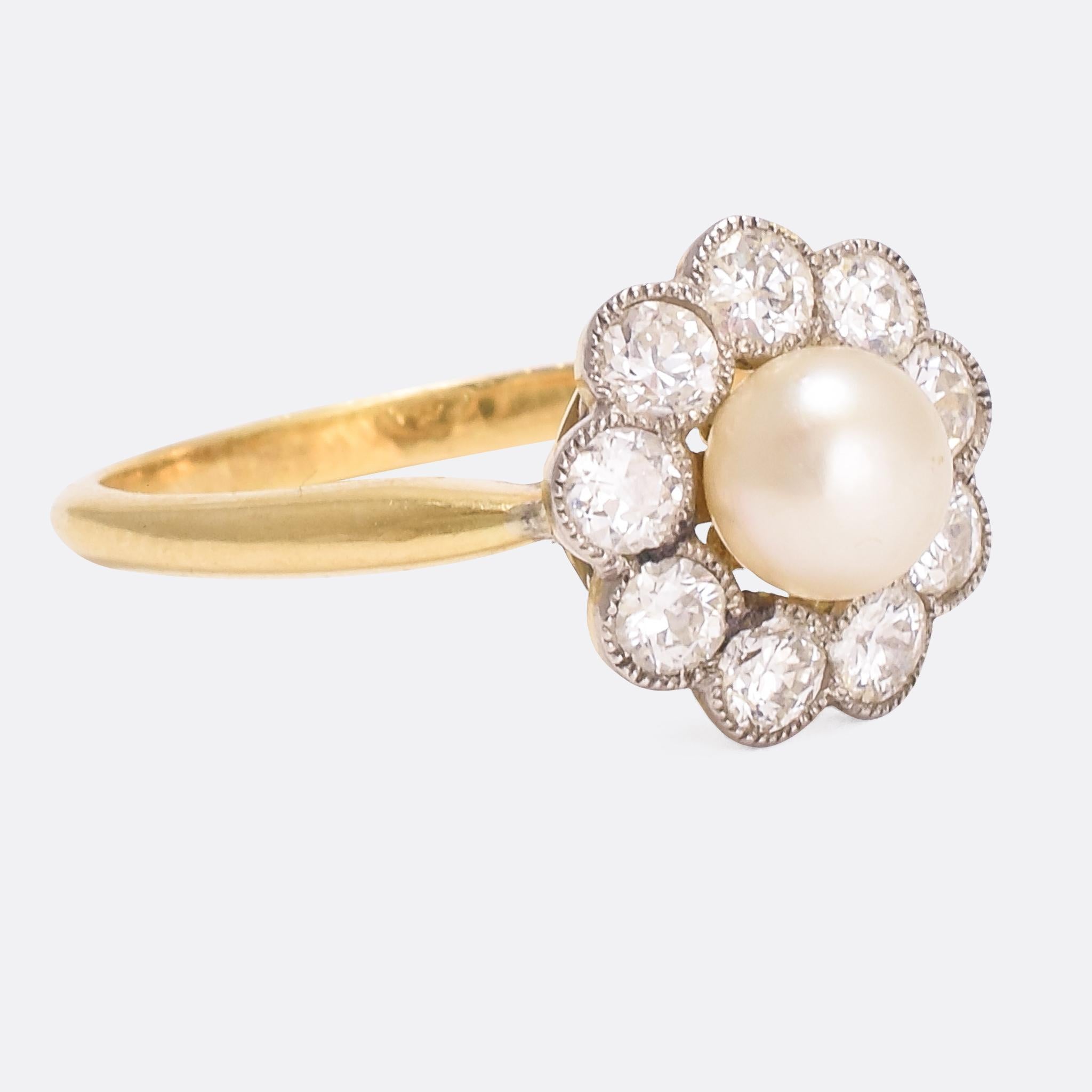 A sweet and perfectly formed antique flower cluster ring set with white diamond petals around a central natural pearl. The diamonds rest in millegrain platinum settings; a gorgeous contrast to the 18k yellow gold band. The openworked gallery allows