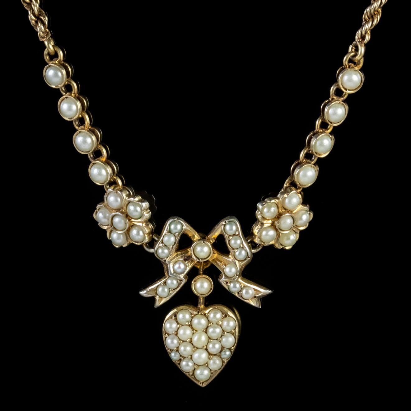A sweet antique Edwardian lavaliere necklace featuring two large forget me nots with a bow and heart dropper hanging in the centre all decorated with lovely Pearls. 

Pearls are a true gift from Mother Nature and symbolize purity innocence and