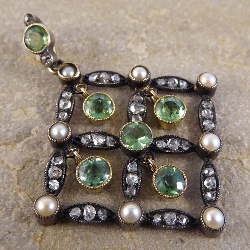 This Elegant Antique Drop Pendant dates to the Edwardian period and has a quality, luxurious feel. The design is balanced by a Diamond and Pearl grid with a Peridot bail and accents. A true classic, this darling pendant rests beautifully on the