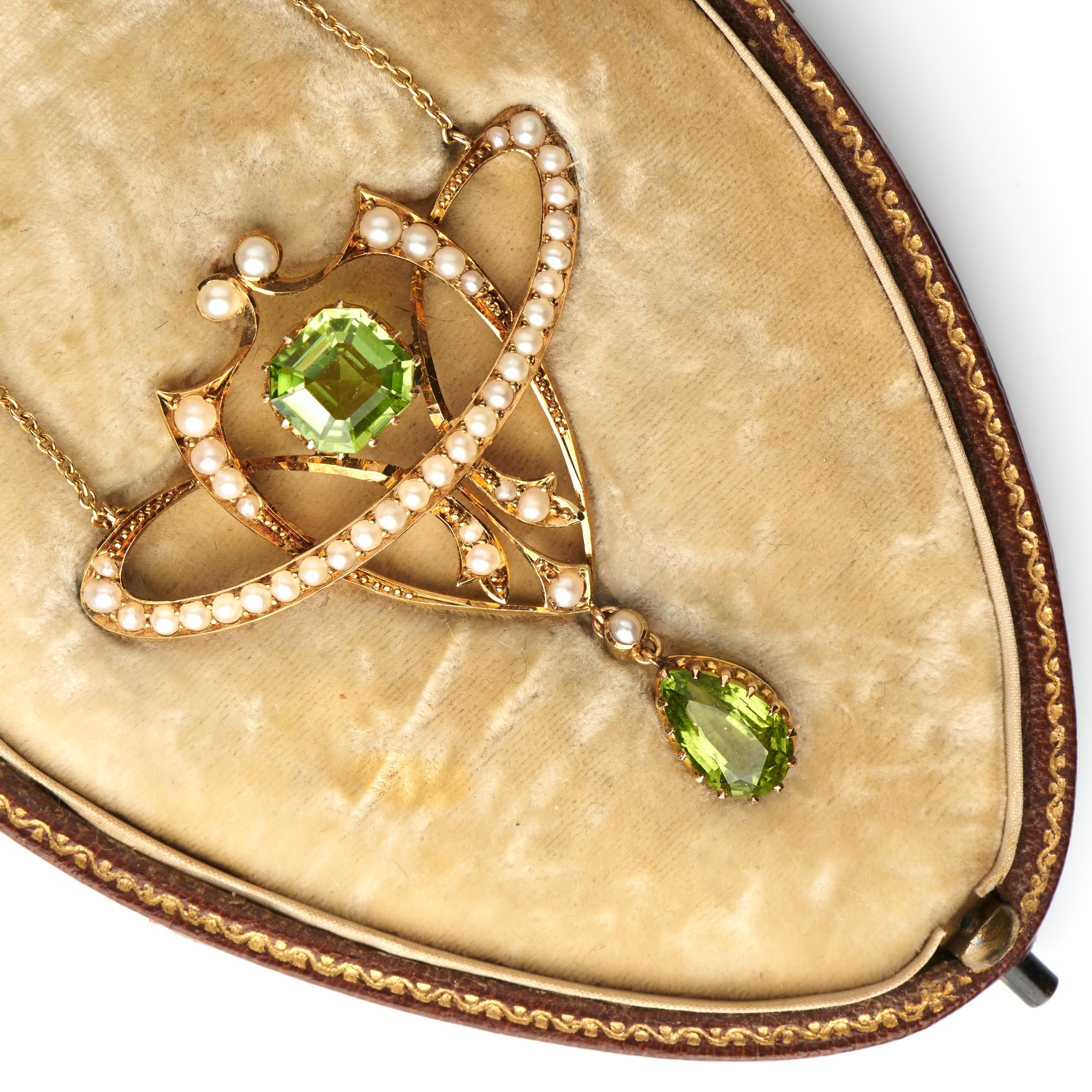 Antique, Edwardian, 15ct yellow gold, peridot and pearl pendant, set with two fancy-cut peridot, complete with original fitted case. A sinuous and contemporary design, a wearable pendant. 