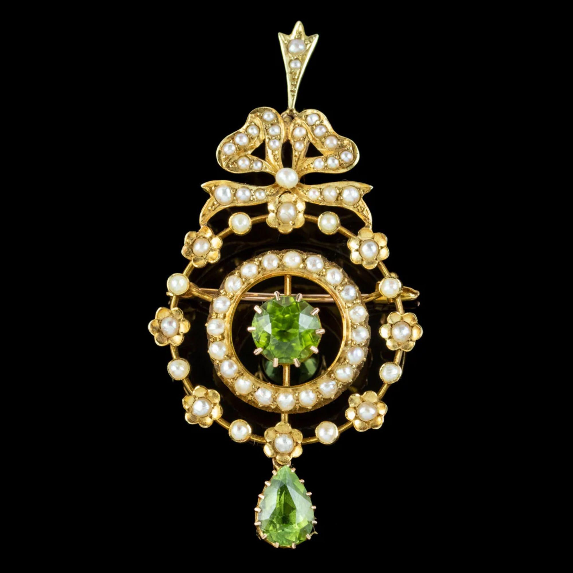 A pretty antique Edwardian pendant from the early 1900s depicting a floral wreath topped with a bow. It’s decorated with an array of gleaming white seed pearls across the front and two rich green peridots, one in the centre and one hanging from a