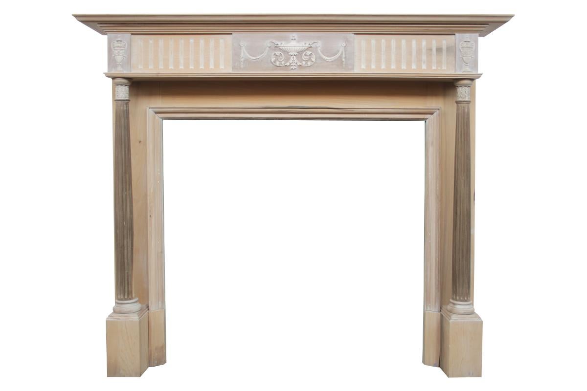 Stripped antique Edwardian pine and gesso fire surround in the Neo-Classical manner. With fluted pillars supporting the deep boxed frieze with a central tablet decorated with urn and swags in delicate gesso work flanked by further fluted panels and