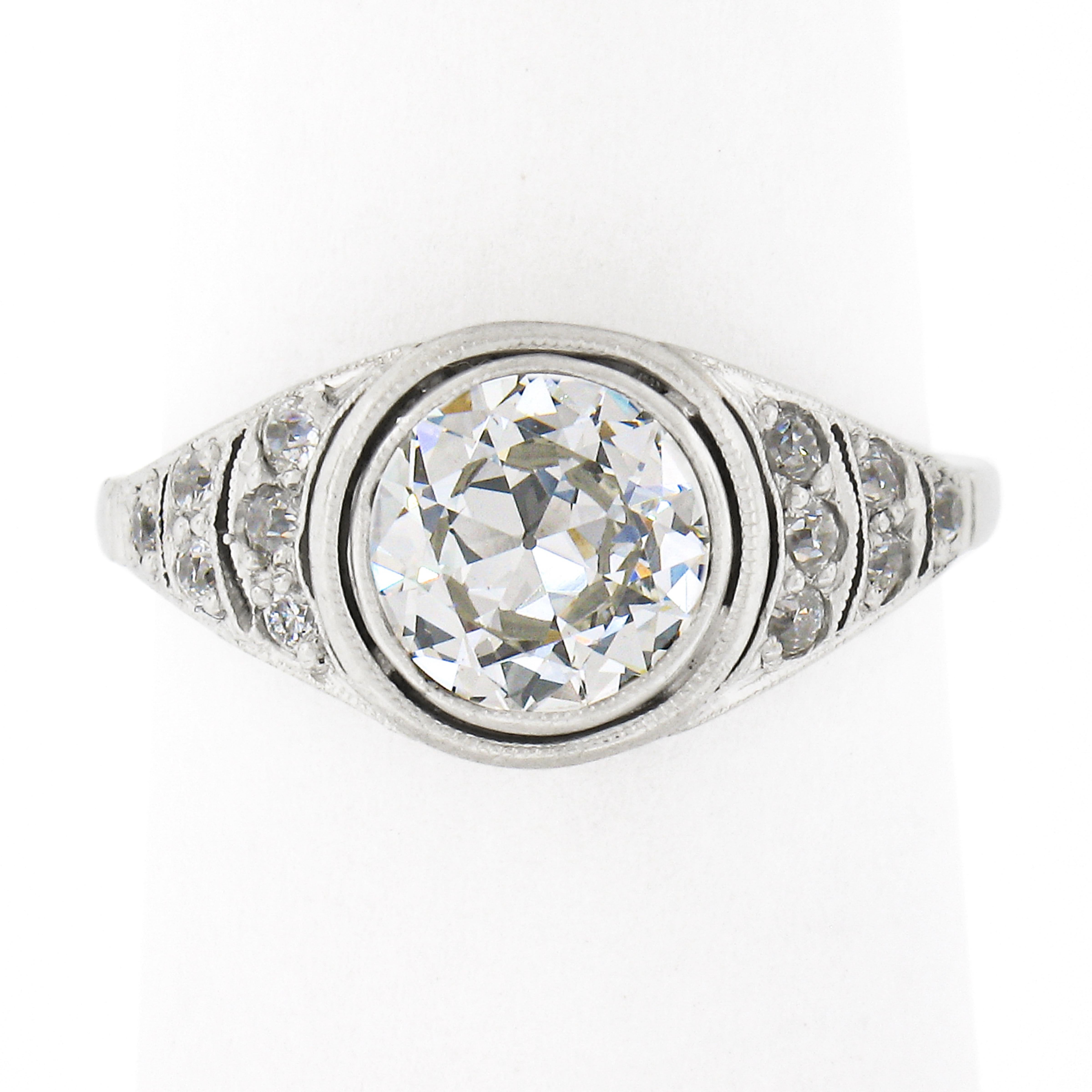 This magnificent antique engagement ring was crafted in solid platinum during the Edwardian period and features a gorgeous old European cut diamond solitaire neatly bezel set at the center of the unique and elegant design. This fine quality diamond