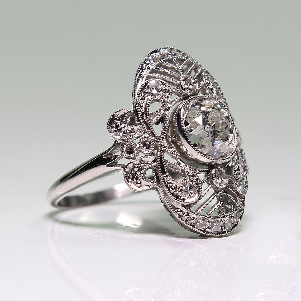 Period: Edwardian (1901-1920)
Composition: Platinum.

Stones:
•	1 cushion Old mine cut diamond of I-SI1 quality that weighs 1.27ctw.
•	24 Single cut diamonds of G-VS2 quality that weigh 0.30ctw.
Ring size: 6 ½   
Ring face:  20mm by 15mm 
Rise above
