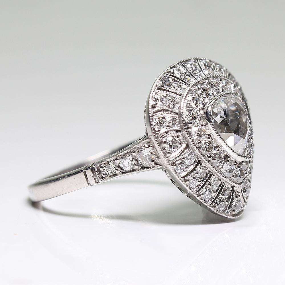 Composition: Platinum.

Stones:
•	1 Rose cut diamond of H-SI1 quality that weighs 0.62ctw.
•	60 Old mine cut diamonds of H-VS2 quality that weigh 1ctw.
Ring size: 7 ¾  
Ring face:  16mm by 15mm 
Rise above finger: 7mm.
Total weight:  5.6grams –
