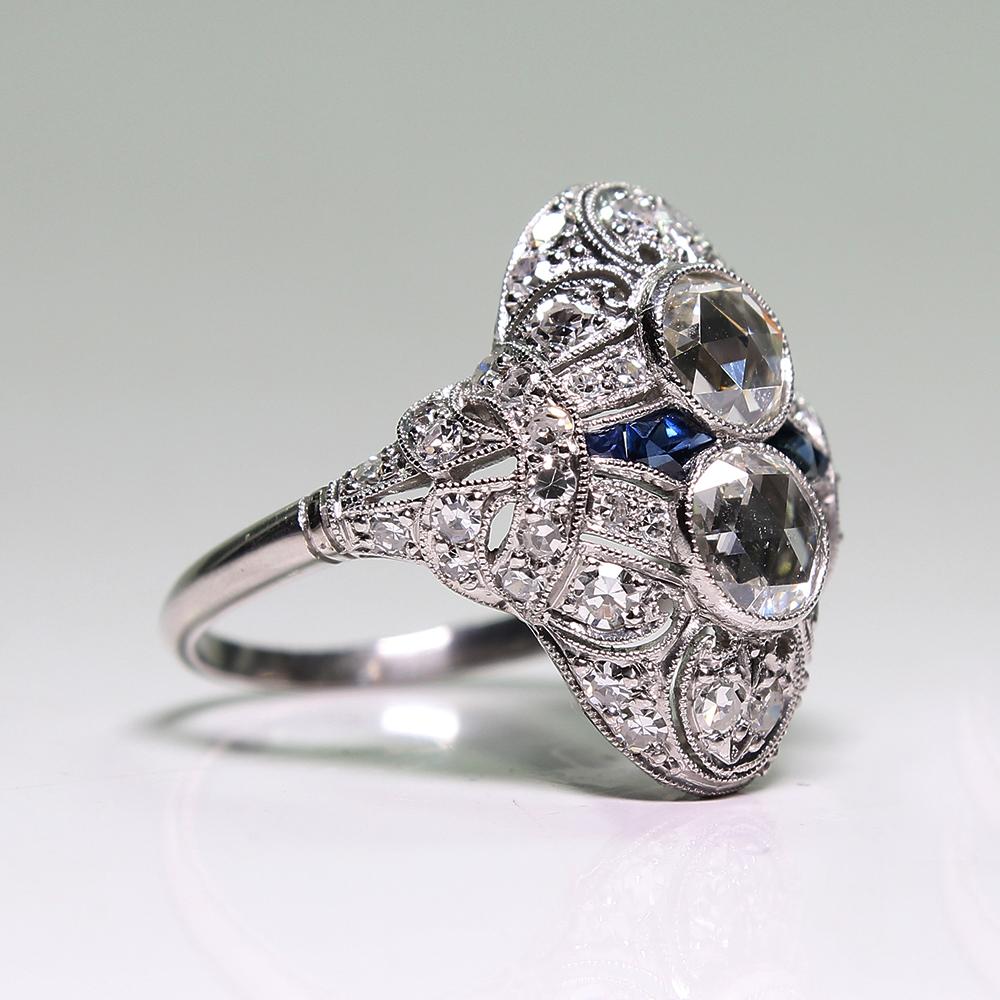 Period: Edwardian (1901-1920)
Composition: Platinum.
Stones:
•	2 Rose cut diamonds of H-VS2 quality that weigh 1.40ctw.
•	44 Single cut diamonds of H-VS2 quality that weigh 0.95ctw.
•	4 natural calibrated French cut sapphires that weigh