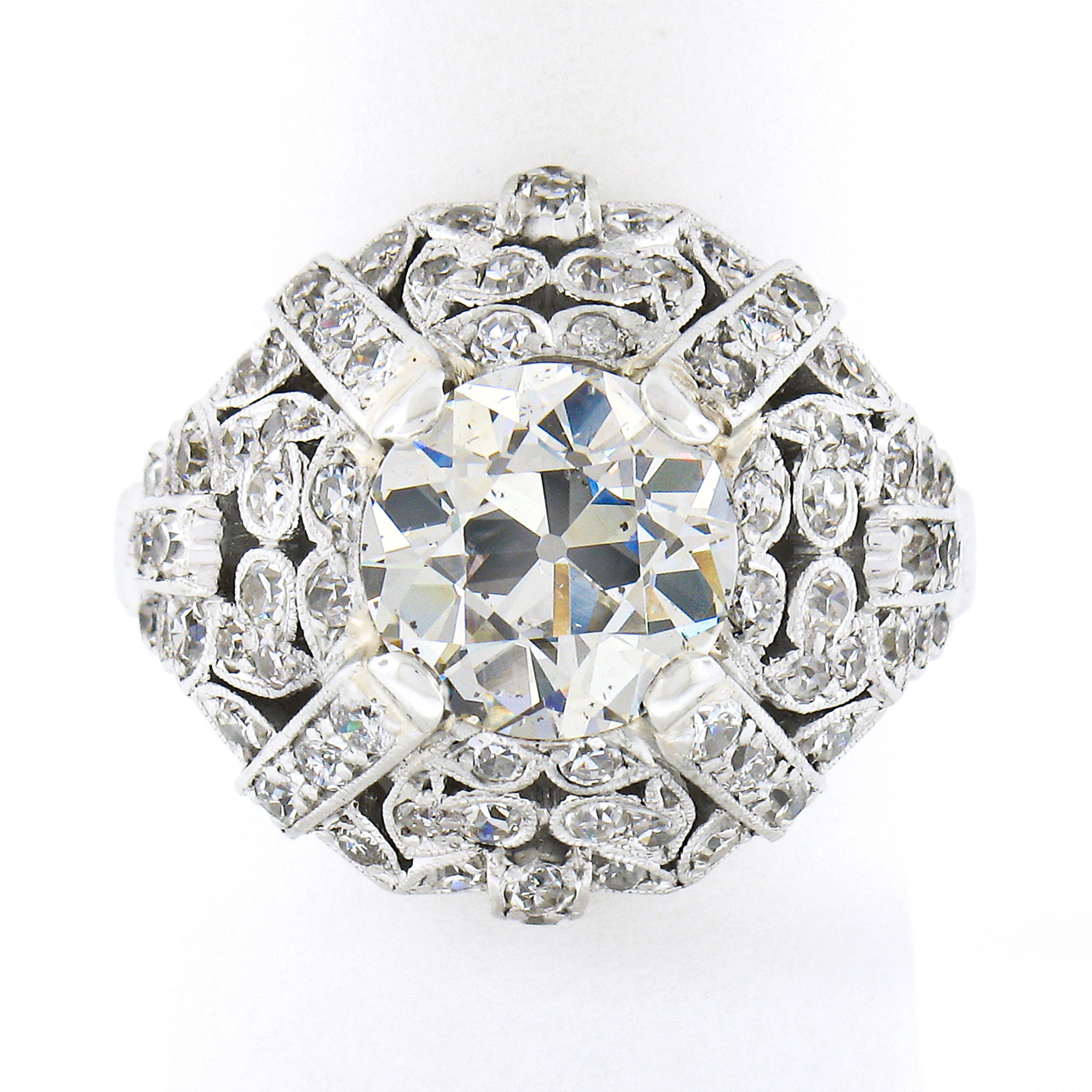 This is an absolutely breathtaking antique engagement or dinner ring that was very well crafted in solid platinum during the Edwardian era. This unique and highly detailed ring features a GIA certified, old European cut, diamond solitaire neatly