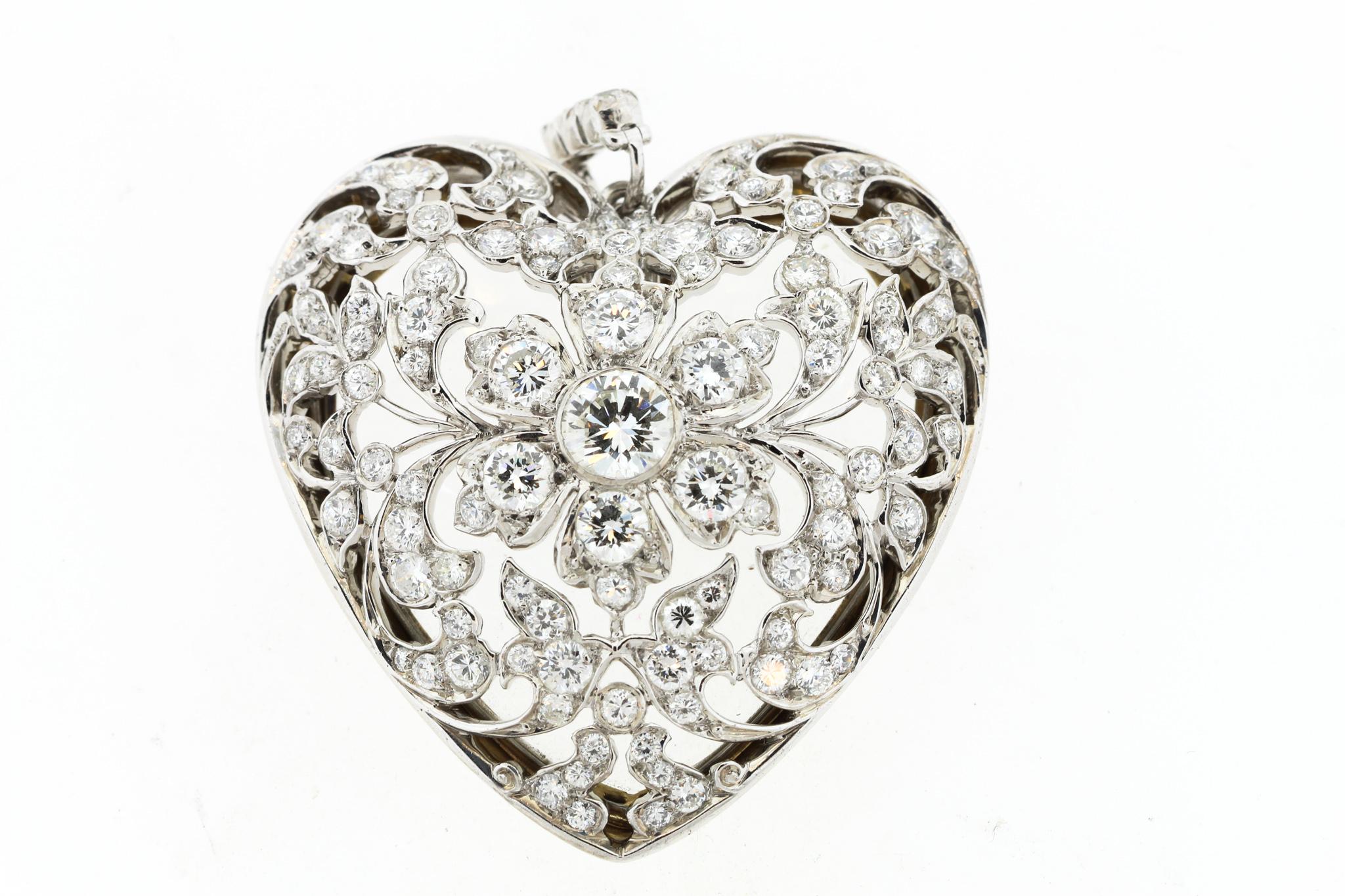 An exceptional platinum and gold diamond heart pendant with its original crystal back circa 1915. This large and romantic open work diamond heart is a true collectors item. The leaf and scroll design centers on a flower with single circular cut