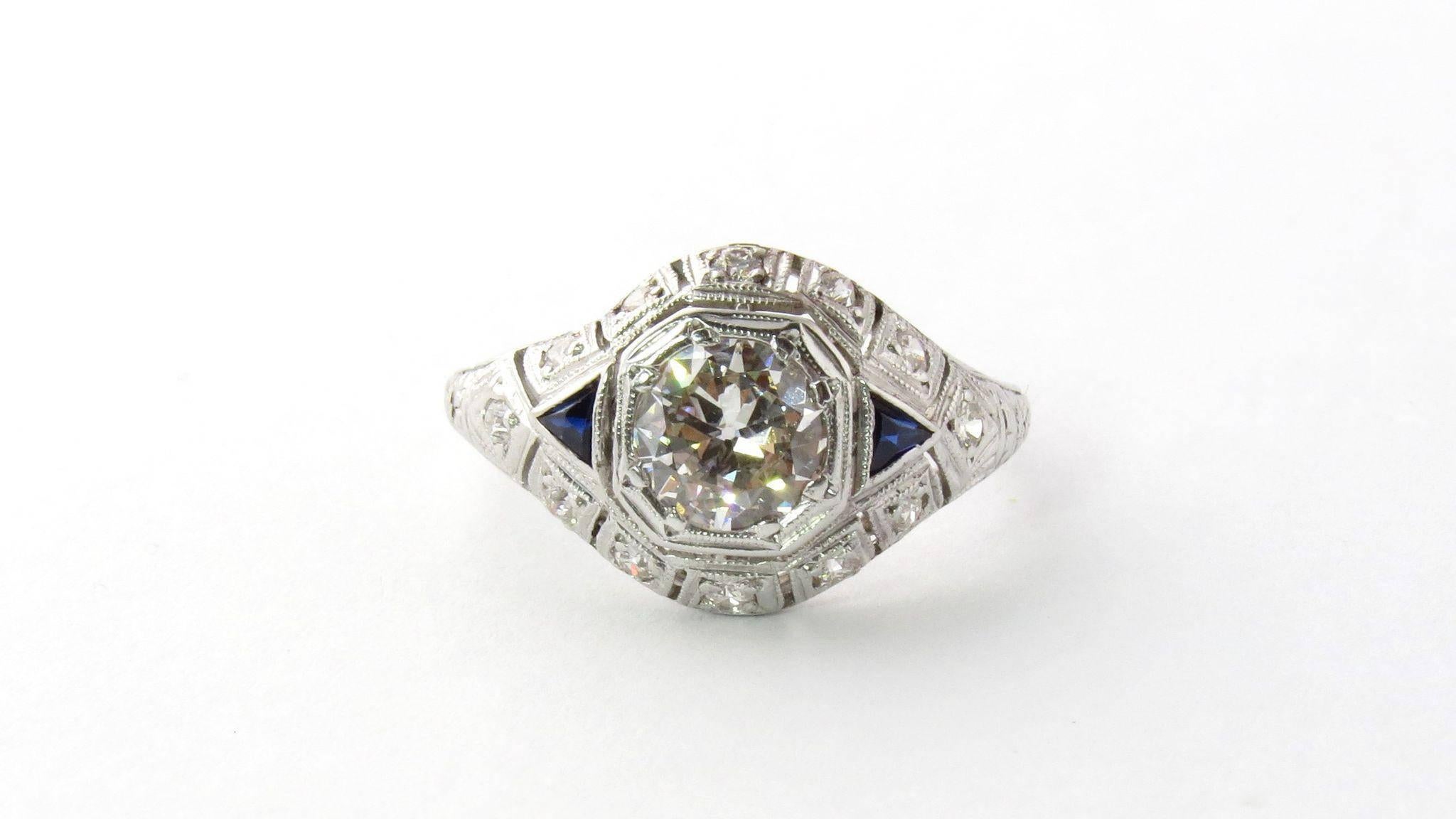 Antique Edwardian Platinum Diamond and Sapphire Dome Ring. 

Set with an approx. 1.00ct. European cut diamond in an octagonal illusion setting. Center diamond is flanked by two triangle cut sapphires and surrounded by smaller diamonds. 

Size 8 3/4