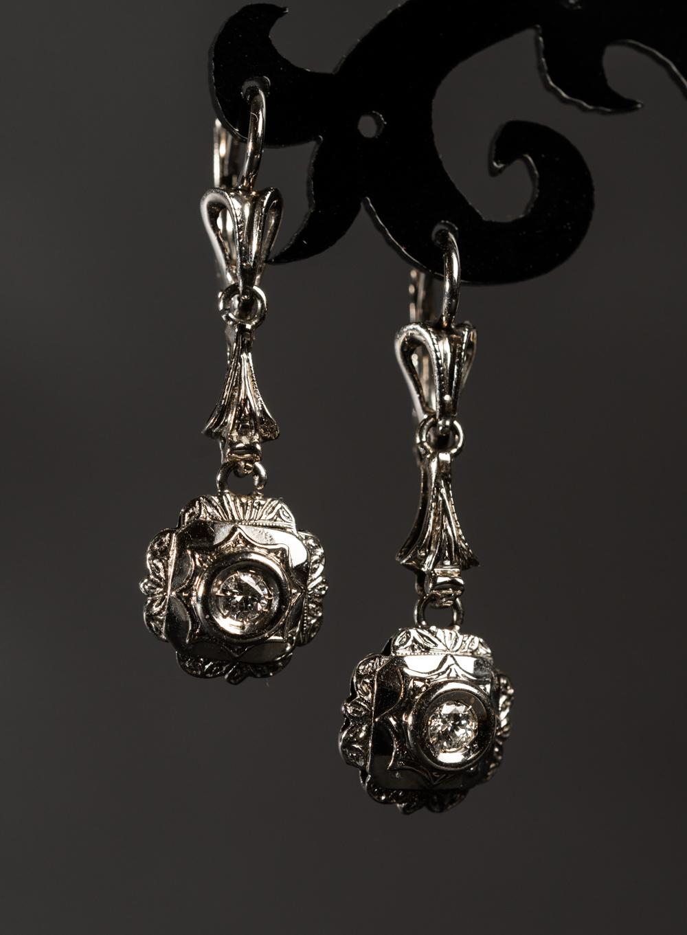 These platinum diamond long drop earrings honor are a fine example of very refined Edwardian jewelry. Strict and well-balanced form of these elongated earrings is complimented with two x 0.15CT diamonds. The lower pendants have floral ornament and