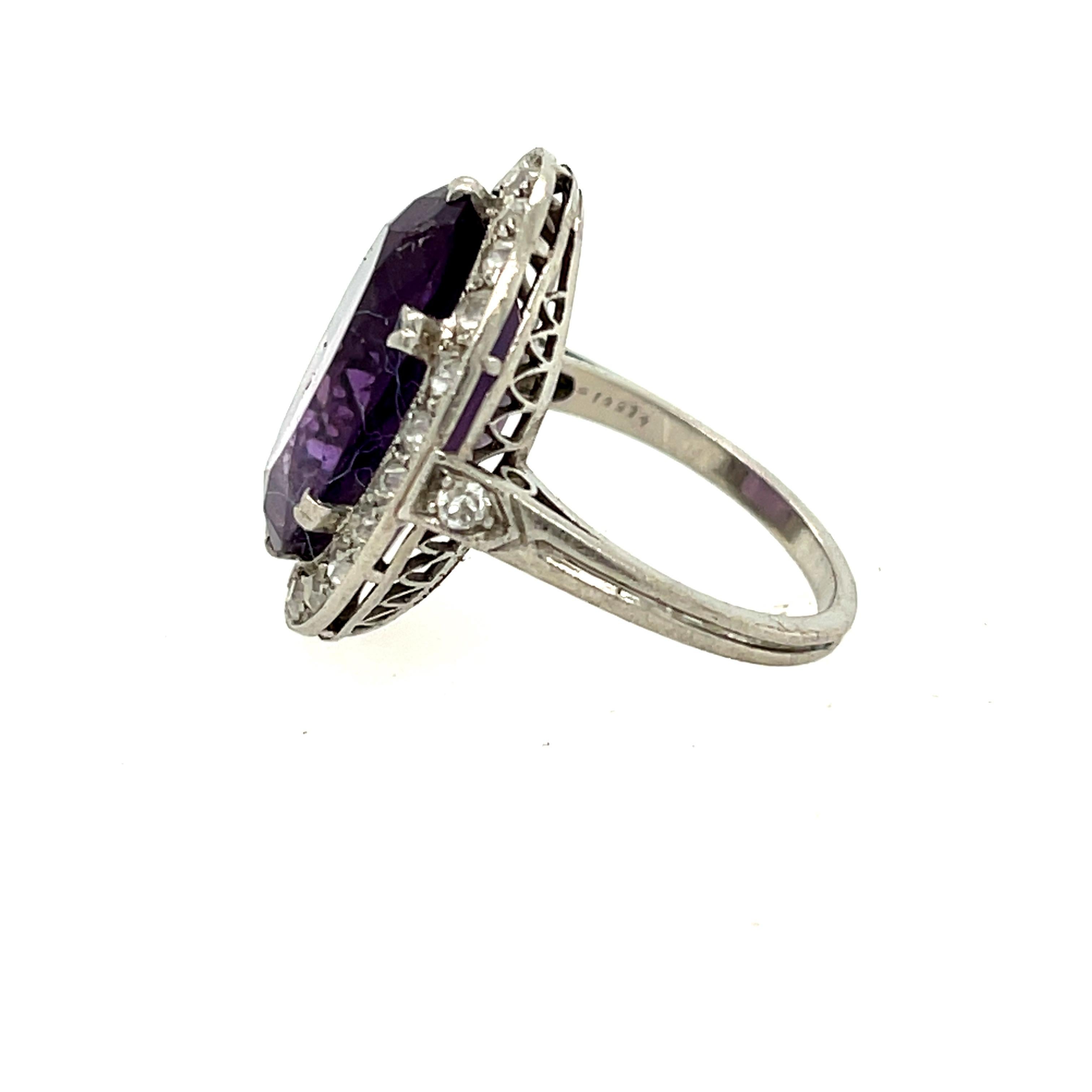Antique Edwardian platinum diamond oval amethyst ring, circa 1910. This gorgeous ring is beautifully made centering on an oval amethyst with a rich purple hue. The ring has a halo of 26 old European cut diamonds weighing 0.90 carats approximately.