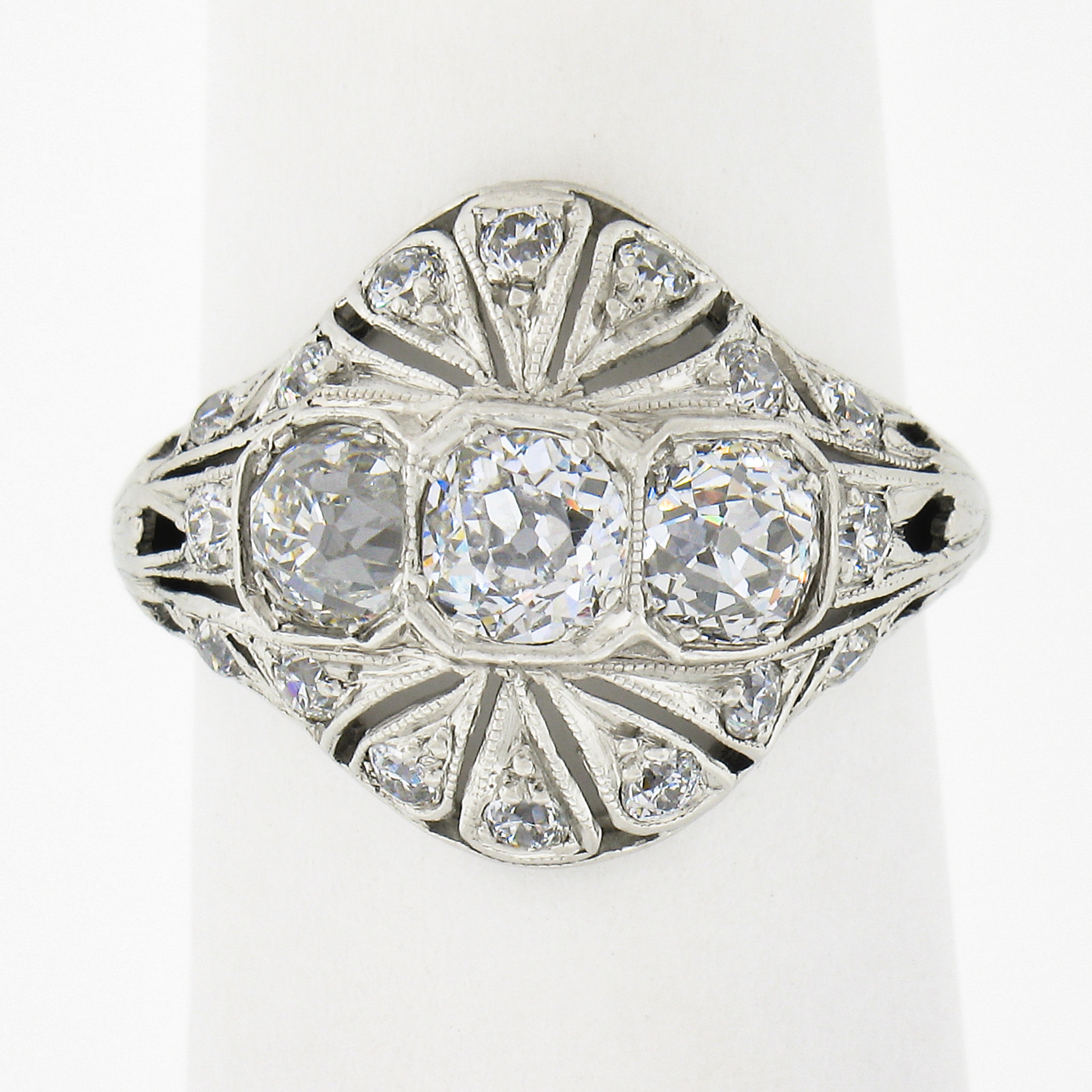 This incredible, all original, antique Edwardian period ring is crafted in solid platinum. It features 3 early old European cut diamonds elegantly pave set across the top in which is further drenched similarly with smaller old cut diamonds