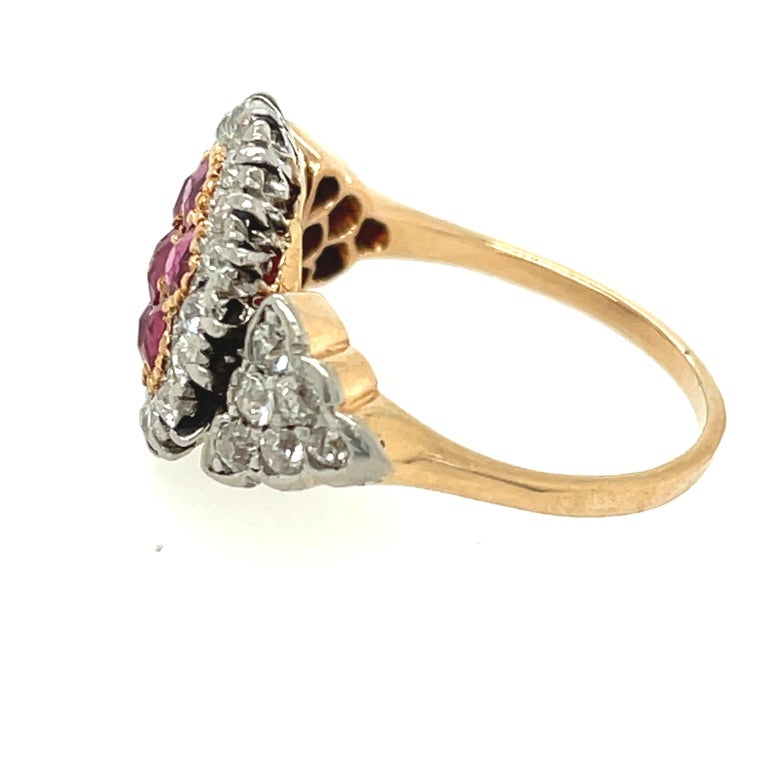 A pretty antique platinum topped gold cluster ruby and diamond ring circa 1910. This unique ring is set with a center cluster of bright red rubies weighing about 0.85 carats. There are old cut diamonds in the mounting around the cluster and on the
