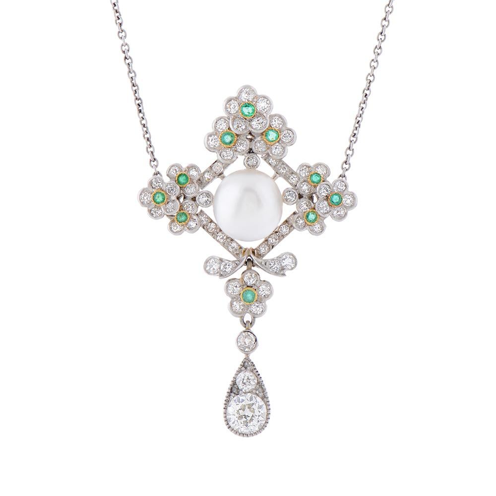 An Edwardian platinum, natural oriental pearl, emerald and diamond pendant. The lobed flowerhead lozenge cluster set at the centre with a button pearl, within a prunus blossom frame adorned with circular-cut diamonds, Further decorated with ten