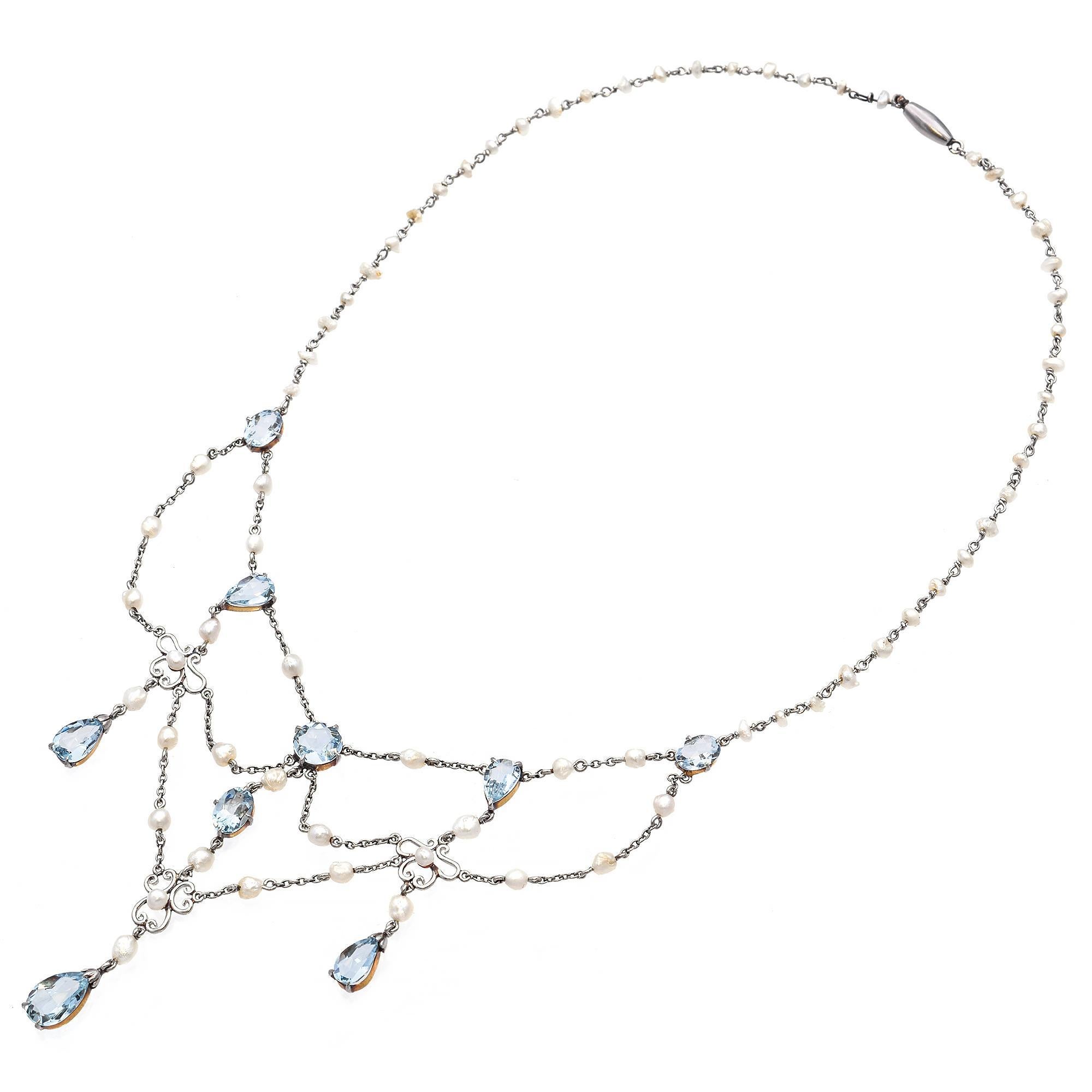 This antique Edwardian festoon necklace is a breathtaking example of early 20th-century grace and craftsmanship. Crafted in platinum, the design showcases the era’s signature airiness and refined draping. The necklace is adorned with delicate seed