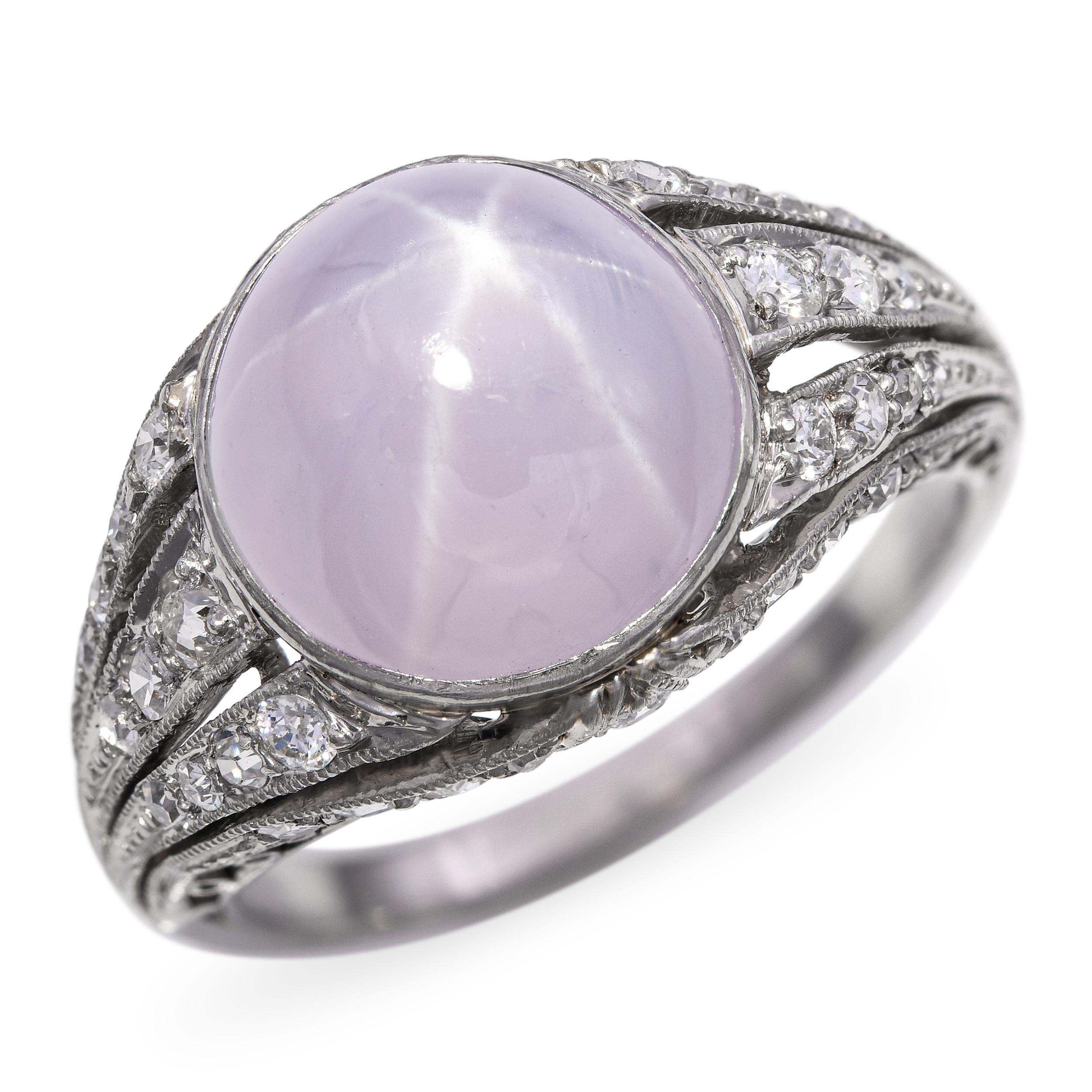 Luminoso esempio di raffinatezza edoardiana, questo anello antico è incentrato su uno zaffiro a stella color lavanda chiaro che mostra un asterismo a sei raggi sulla sua superficie cabochon a cupola. Il bagliore etereo dello zaffiro è perfettamente