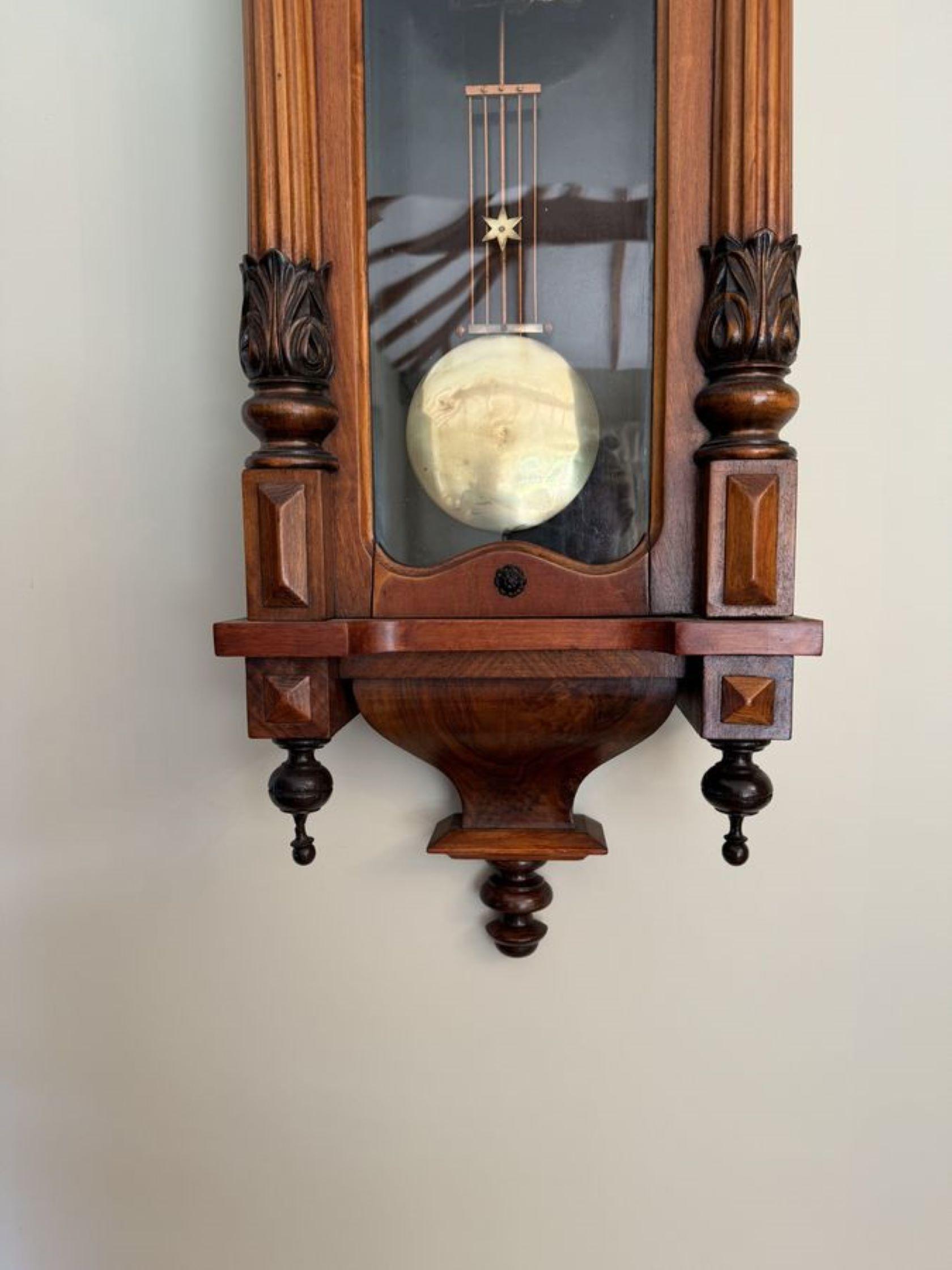Antique Edwardian quality carved walnut Vienna wall clock having turned columns, original finale's with a shaped top with a horse and figure finial and a shaped bottom . Single walnut glazed door opening to reveal a circular porcelain dial with the