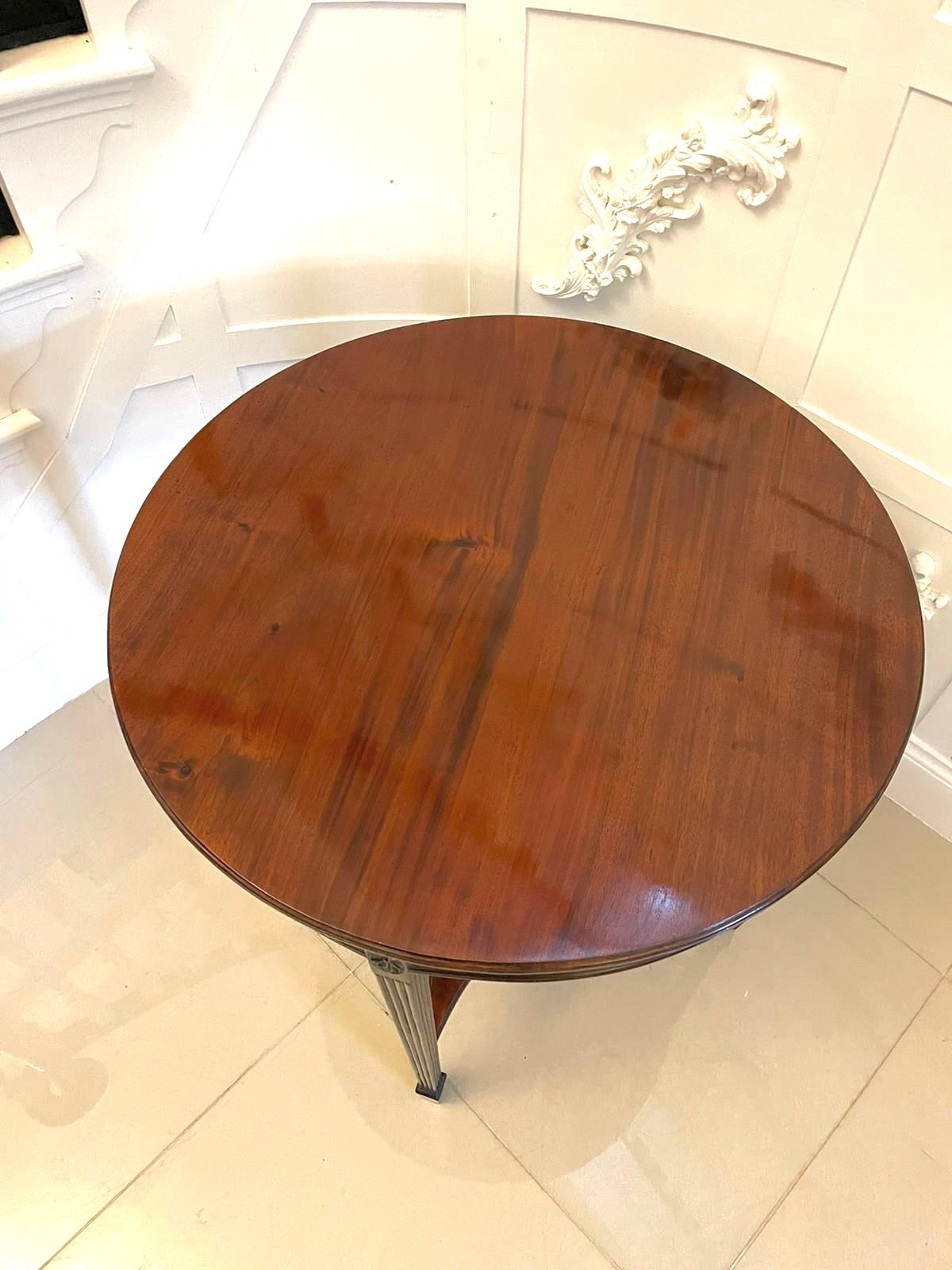 Antique Edwardian quality figured mahogany circular centre table having a quality circular figured mahogany top with a moulded edge, carved and reeded frieze standing on square tapering carved and reeded mahogany legs with spade feet and united by a