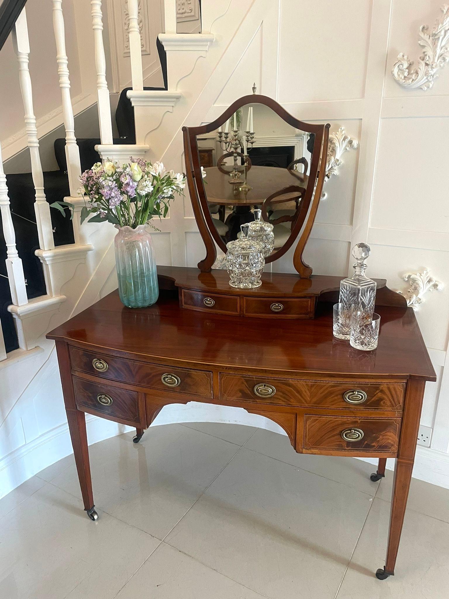 Antique Edwardian quality mahogany inlaid dressing table having a shield shaped adjustable mirror with scroll shaped supports above two small figured mahogany bow fronted drawers crossbanded in satinwood with ornate pretty oval brass handles.  The