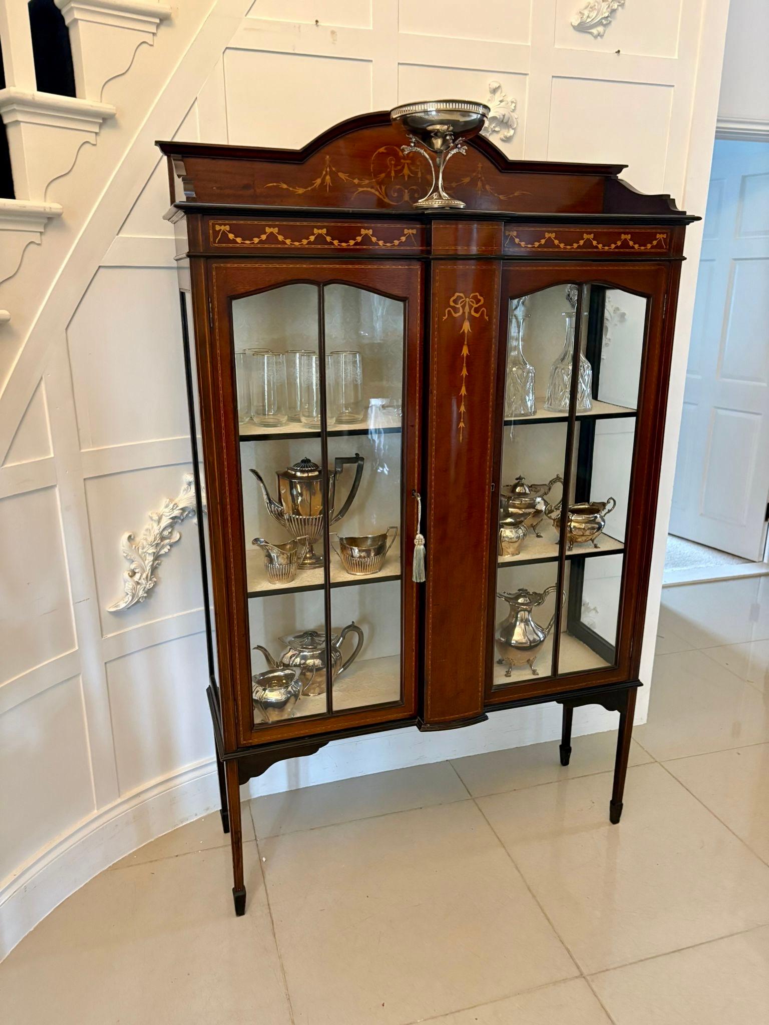 Antique Edwardian quality mahogany inlaid satinwood display cabinet having a quality mahogany inlaid satinwood shaped top above an inlaid frieze above a bow fronted mahogany inlaid satinwood centre flanked by a pair of glazed doors opening to reveal