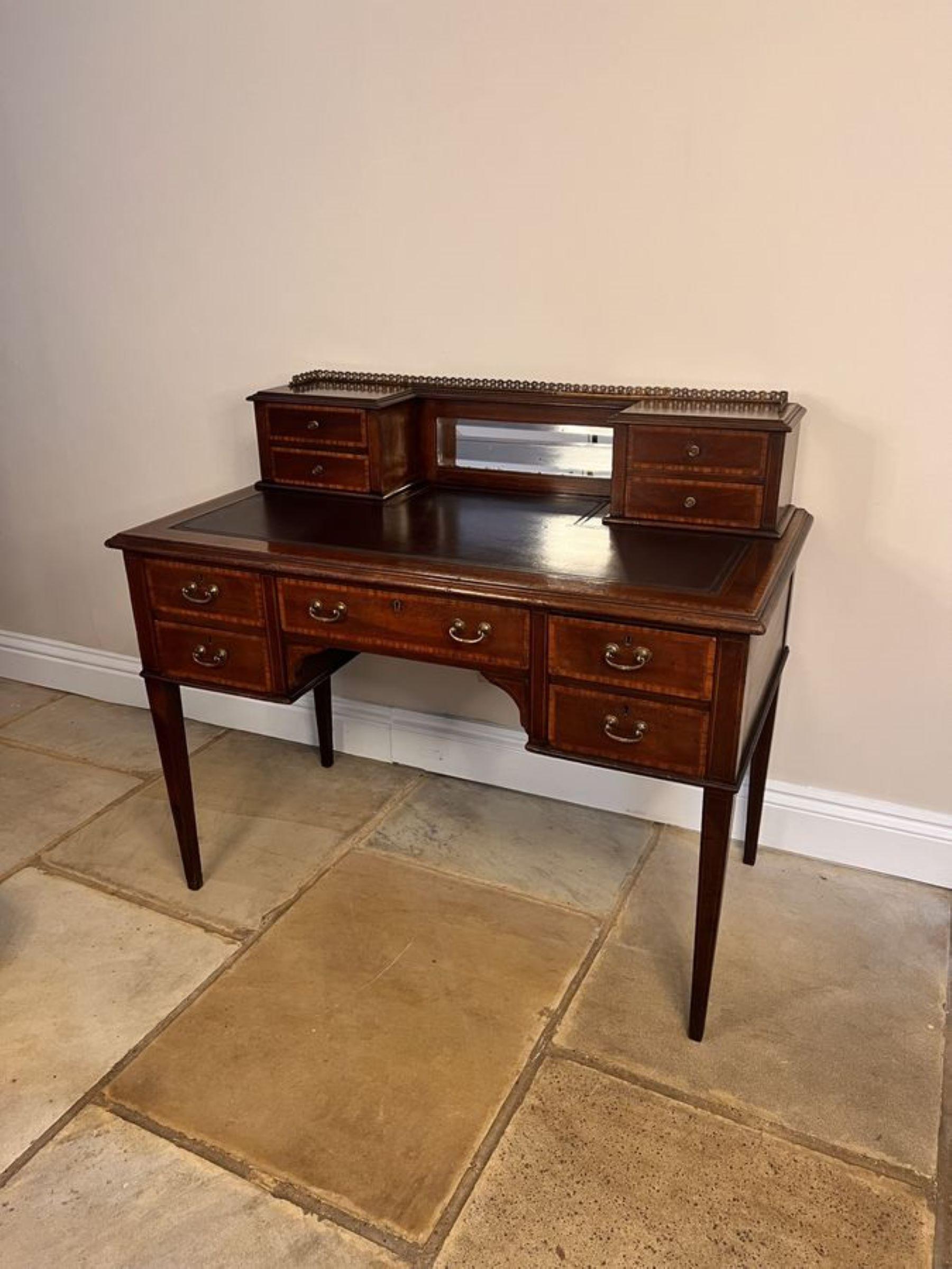 Antique Edwardian quality mahogany inlaid writing desk, having the original brass gilded gallery above a small bevelled edge mirror flanked by four small mahogany inlaid drawers above a leather top writing surface cross banded in mahogany above five