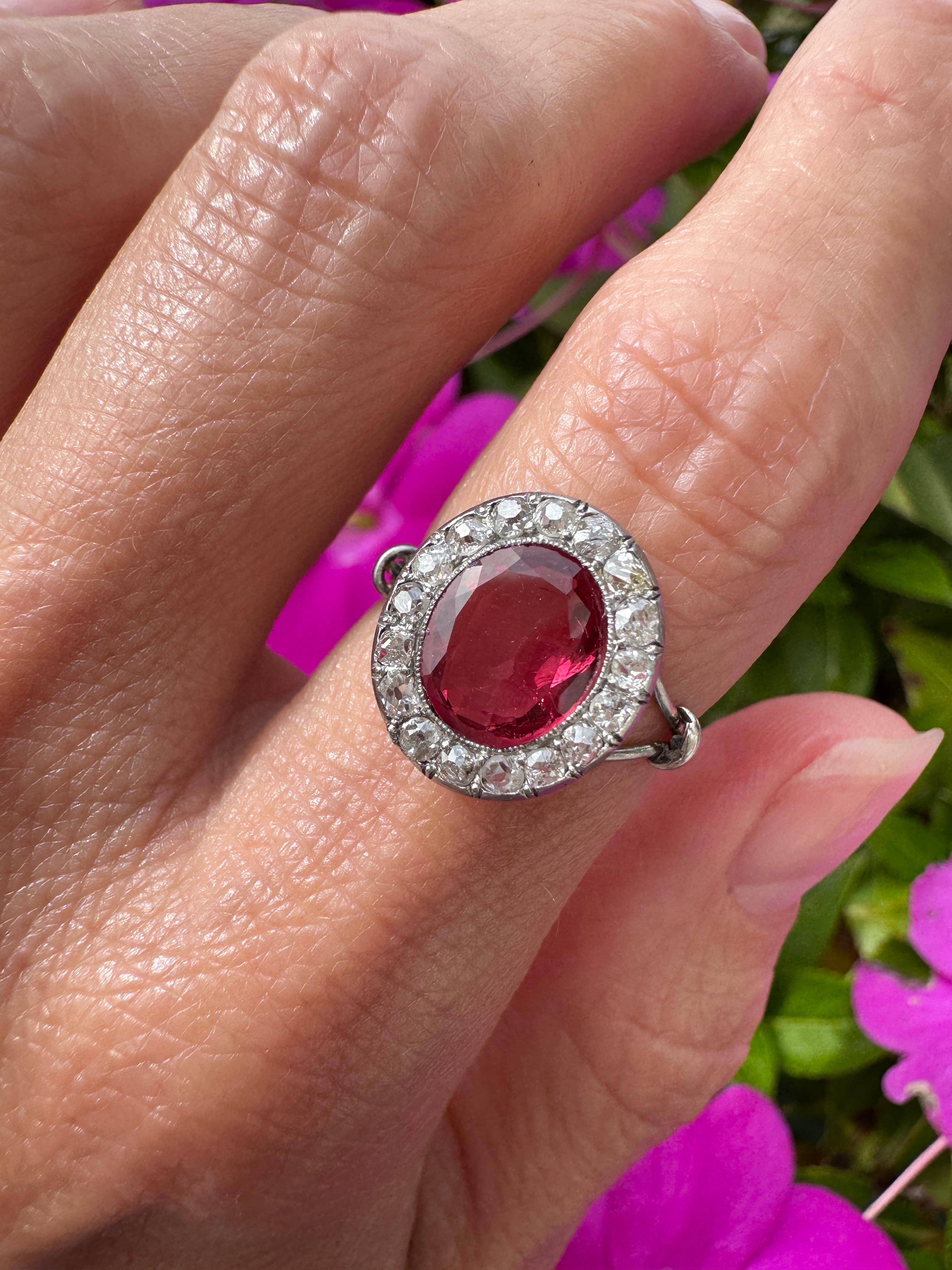 Uno spinello cremisi eccezionalmente vivo, del peso di circa 1,50 carati, brilla all'interno di un'elegante castone in platino. La vibrante pietra centrale è circondata da una delicata aureola di piccoli e scintillanti diamanti taglio antico. Le