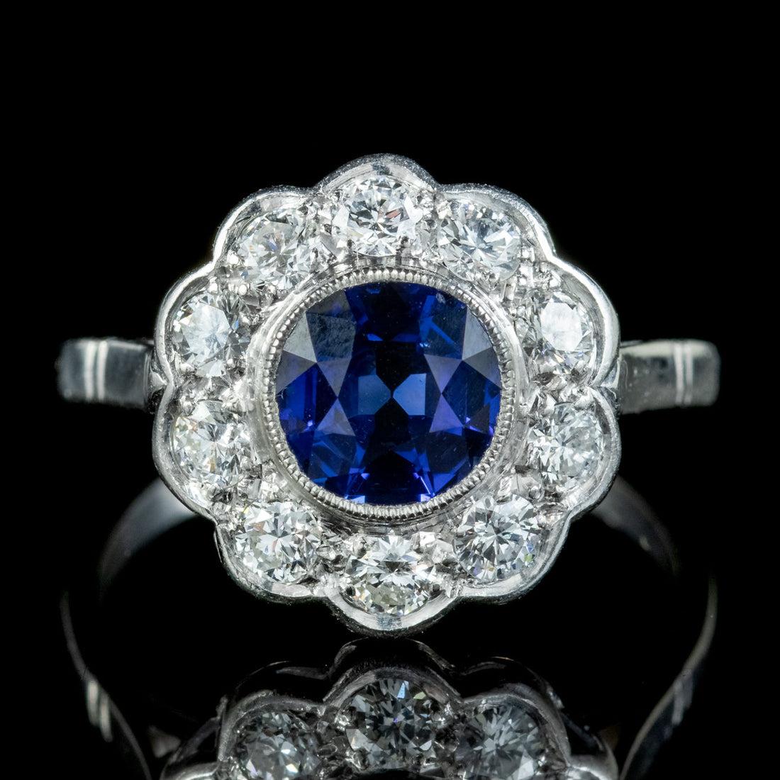 A gorgeous Antique Edwardian daisy ring from the early 20th Century boasting a vibrant, deep blue Sapphire collet set in the centre with a halo of sparkling brilliant cut Diamond petals.

The Sapphire is approx. 1.25ct and is complemented