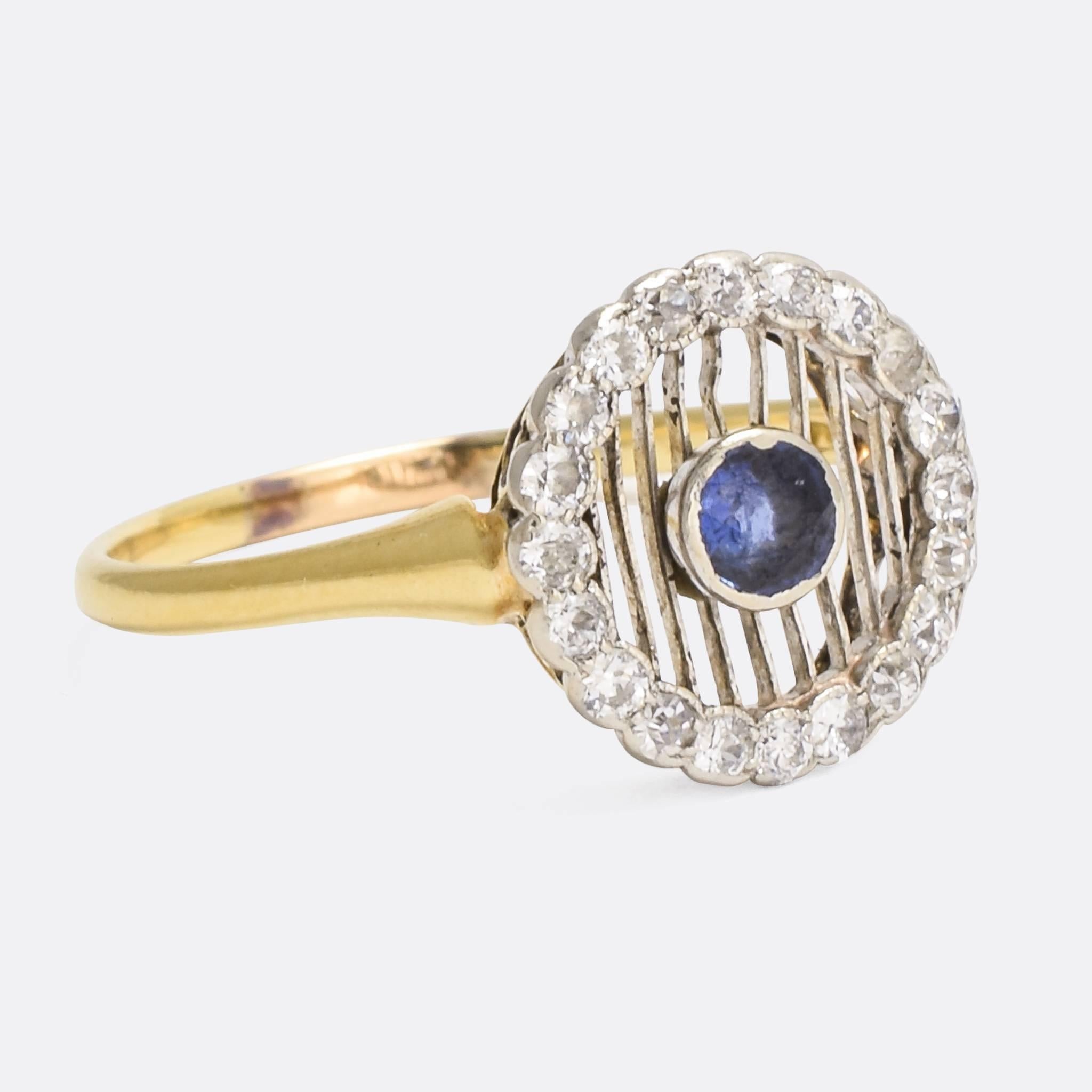 A stylish antique halo ring, set with a central blue sapphire and a cluster of old cut diamonds. The sapphire is suspended on ultra-thin platinum bars, and unusual but very cool design. It dates from the Edwardian era, crafted in 18 karat gold and