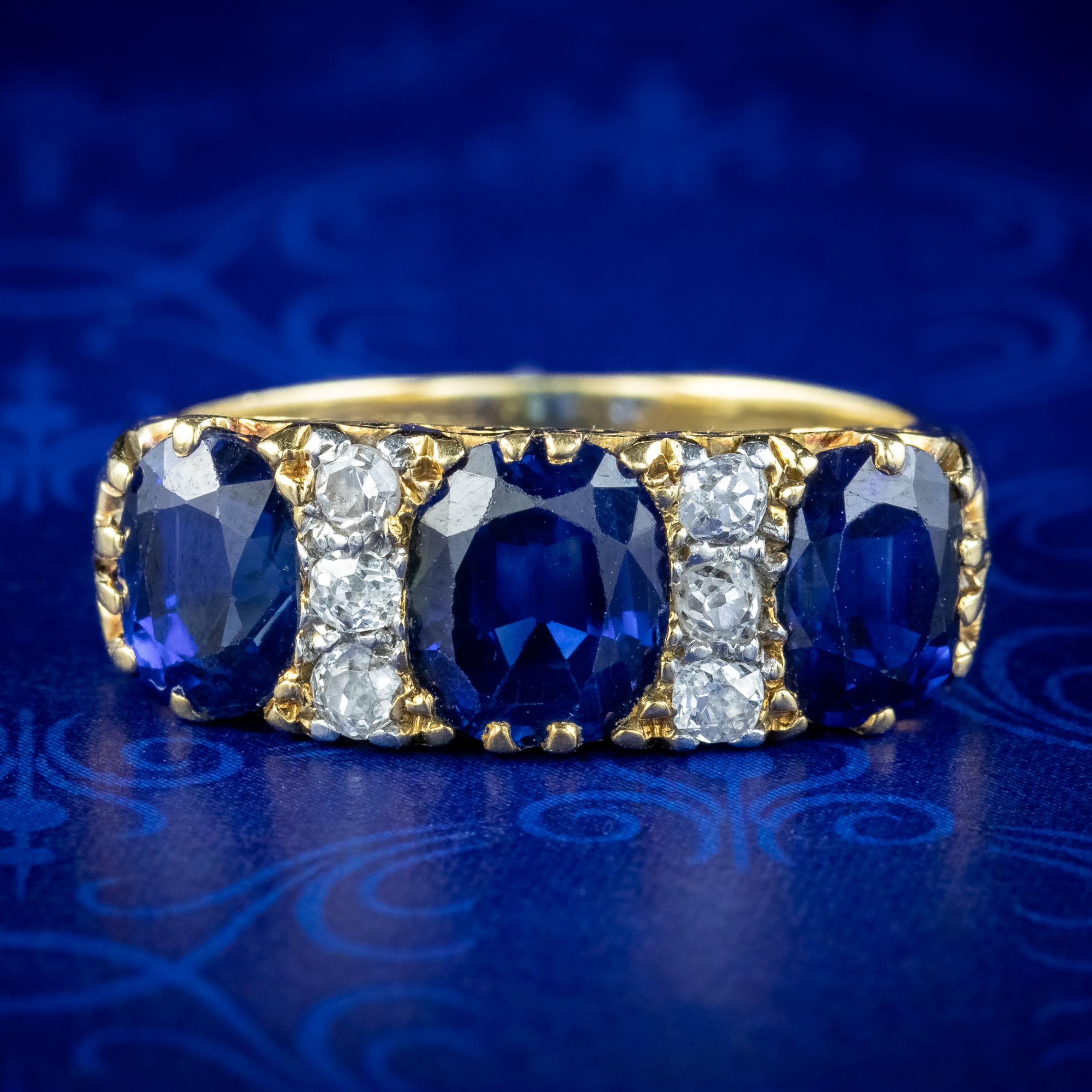 A magnificent antique Edwardian carved half hoop ring boasting a trilogy of natural blue sapphires weighing approx. 1.1ct in the centre and 0.80ct at the sides (approx. 2.7ct total). They have a regal deep blue hue and are complemented by six