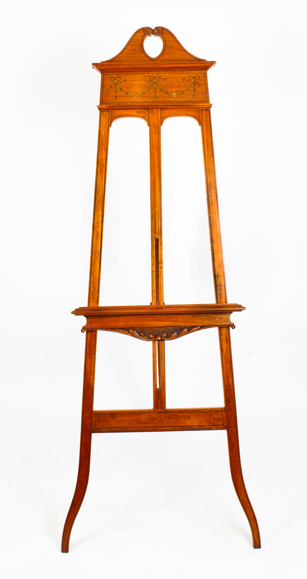A beautiful antique Edwardian satinwood display easel, circa 1900 in date.

The easel features superb hand painted and carved decoration with an adjustable shelf.

It is superbly hand painted with garlands of flowers, bows and ribbons, and
the