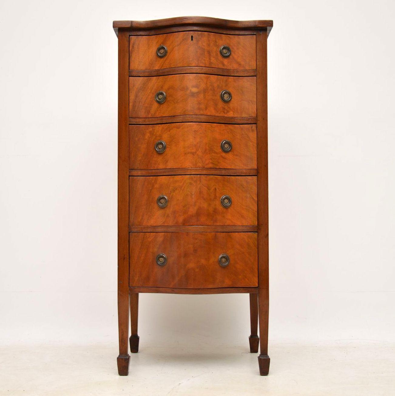 Slim antique Edwardian mahogany chest of drawers with a serpentine shaped front and sitting on spade end legs. It’s in good original condition and has nice warm colour. The drawers are graduated in depth and have the original brass handles. Antique