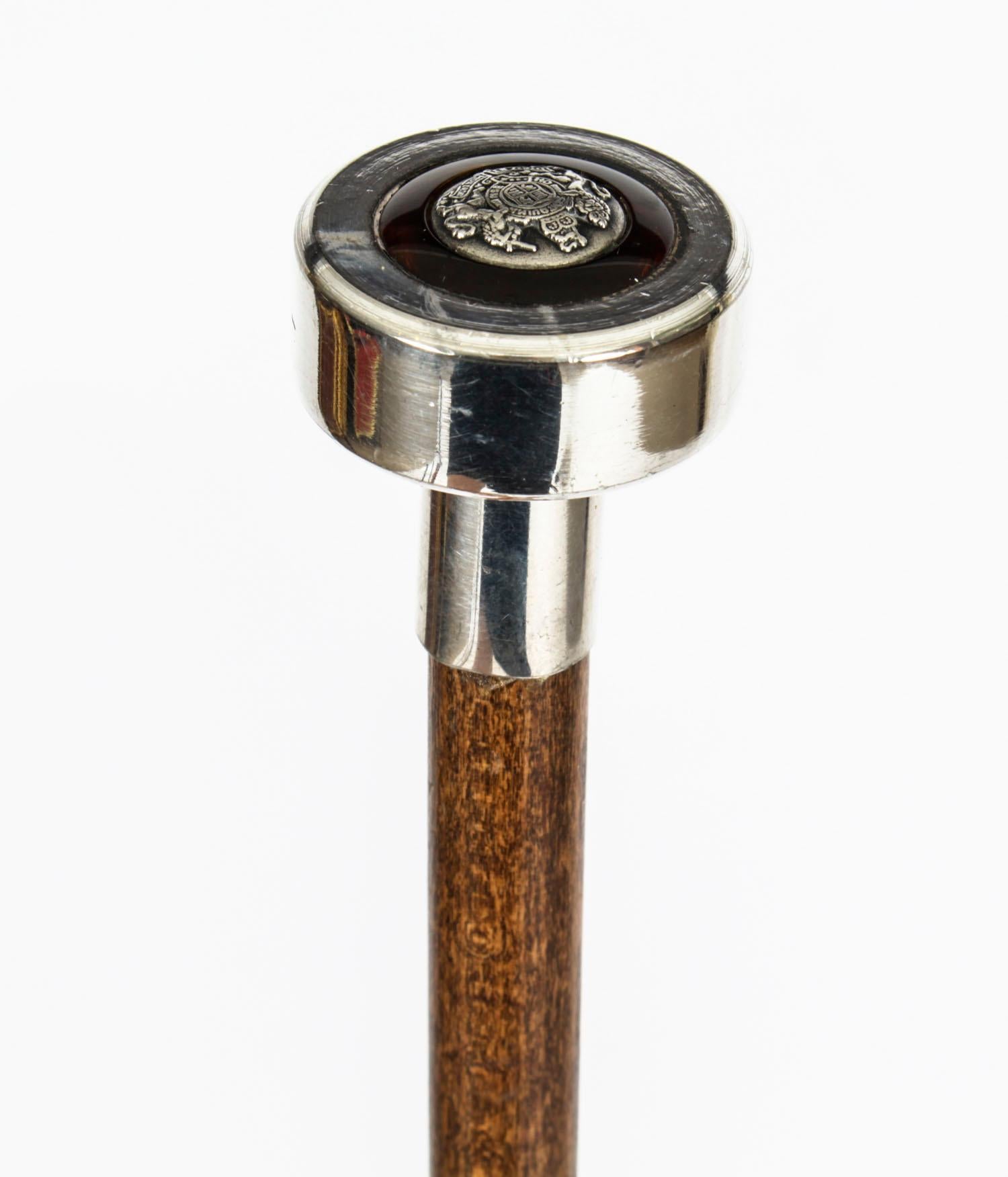 This is a superb Edwardian silver plated, amber Malacca walking stick, dating from the late 19th century.
 
This decorative walking cane features a splendid globular cast pommel with a Royal coat of arms inset with amber. The sturdy Malacca