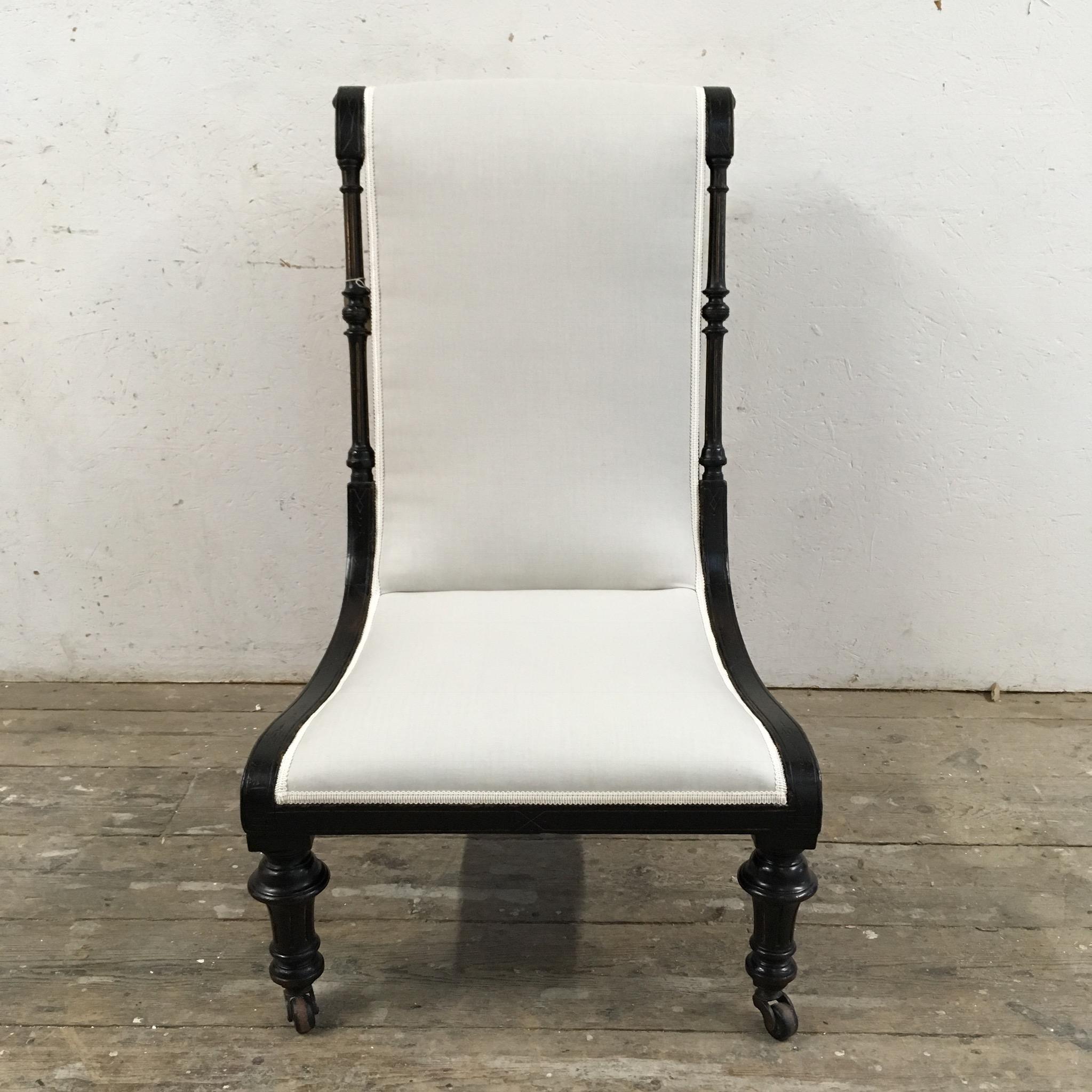 Beautiful Edwardian slipper chair

Ebonised wooden frame

Re-upholstered in a soft light colored herringbone cotton with matching trim 

The chair has hand carved side spindles and turned legs with original castors 

There are also carved